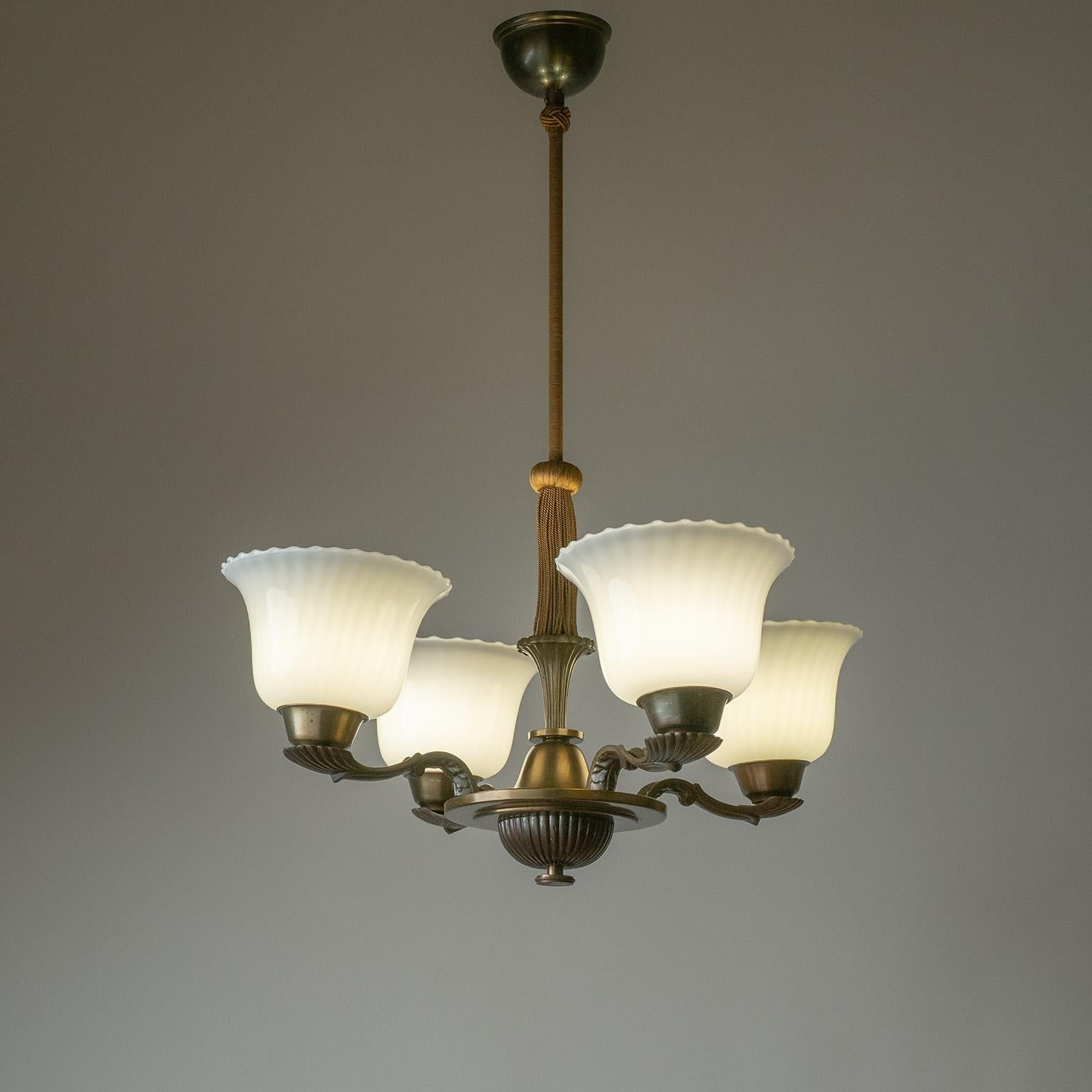 Elegant lustre suédois Art déco des années 1930. Structure en laiton patiné joliment détaillée avec des diffuseurs en verre légèrement frangés. Très bel état d'origine avec juste quelques légères usures. Quatre douilles E27 en laiton d'origine avec
