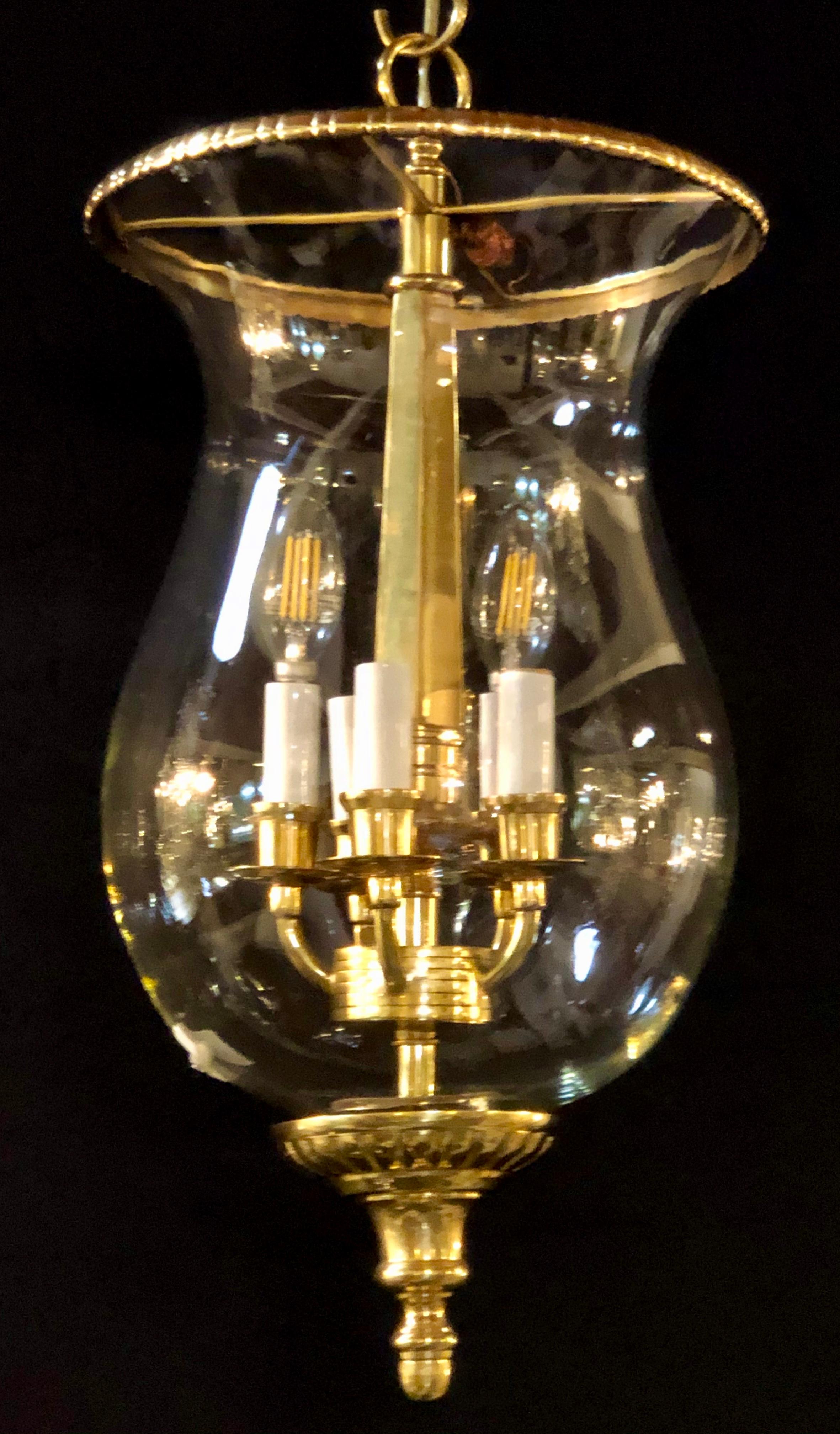 A pair of brass and glass bell jar five-light chandeliers or pendants. These finely decorative bell jar lights each have three lights on the interior with bronze framing supporting the crystal glass center urns. 


3029 HXX.