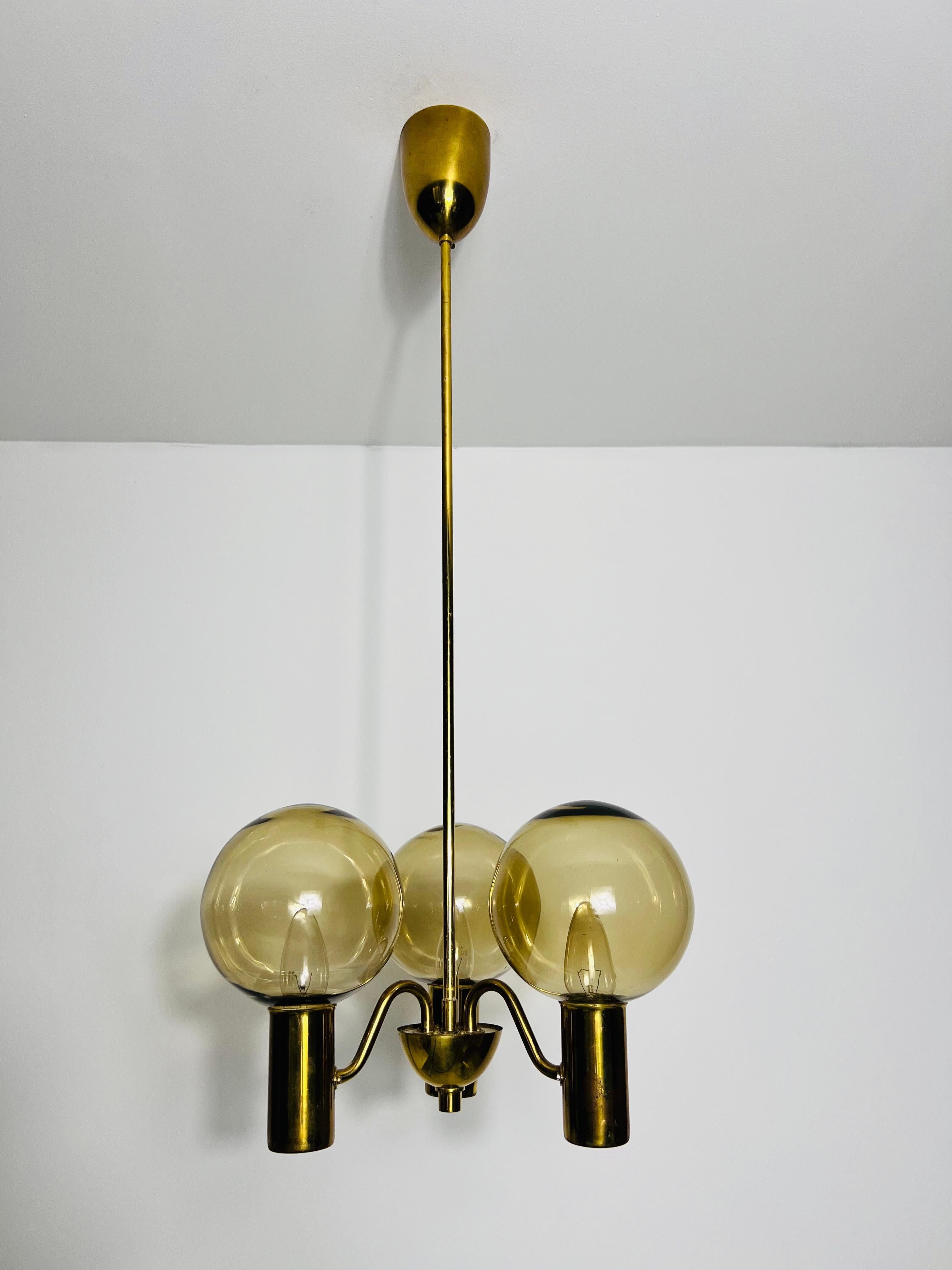 This exquisite brass and glass chandelier, designed by the renowned Swedish designer Hans-Agne Jakobsson in the 1960s, is a true design icon. Jakobsson, celebrated for his innovative lighting creations, crafted this chandelier with a perfect blend
