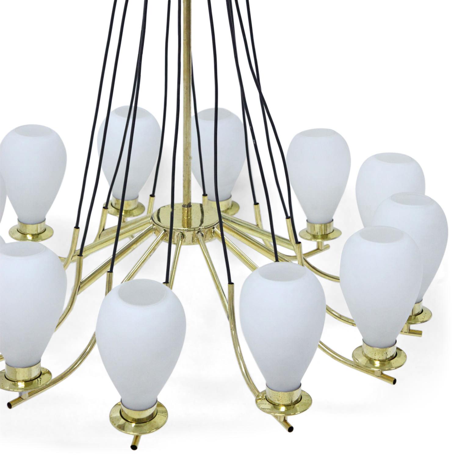 Large twelve-arm chandelier out of brass with cone-shaped lampshades out of opaque glass. The black wiring meets at the height of the ceiling mount. 

For the electrification we assume no liability and no warranty.