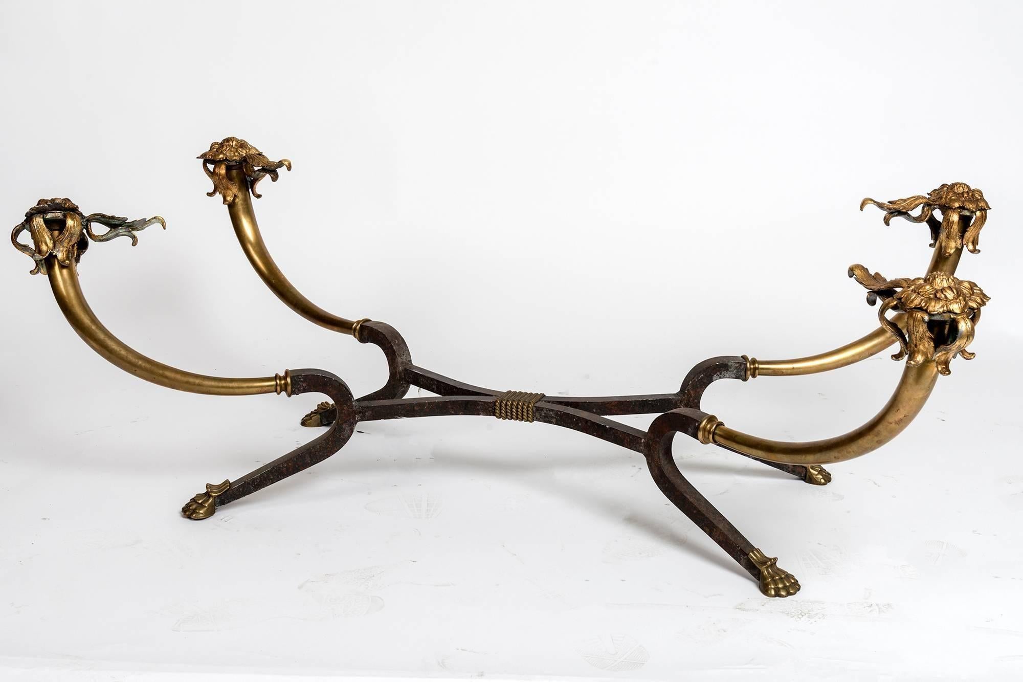 Brass and glass coffee table with flower decoration at the top and claw feet.