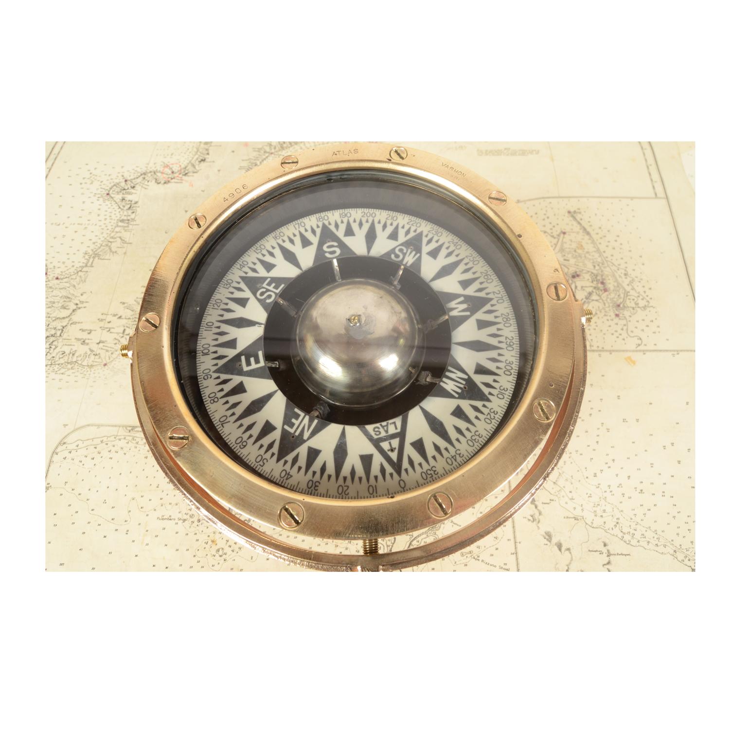 Large brass and glass compass on universal joint signed Atlas Vashon (Washington)n. 4986. Mounted on mahogany board made and to measure. The compass consists of a cylindrical brass container, called a mortar, with double glass on the bottom of which