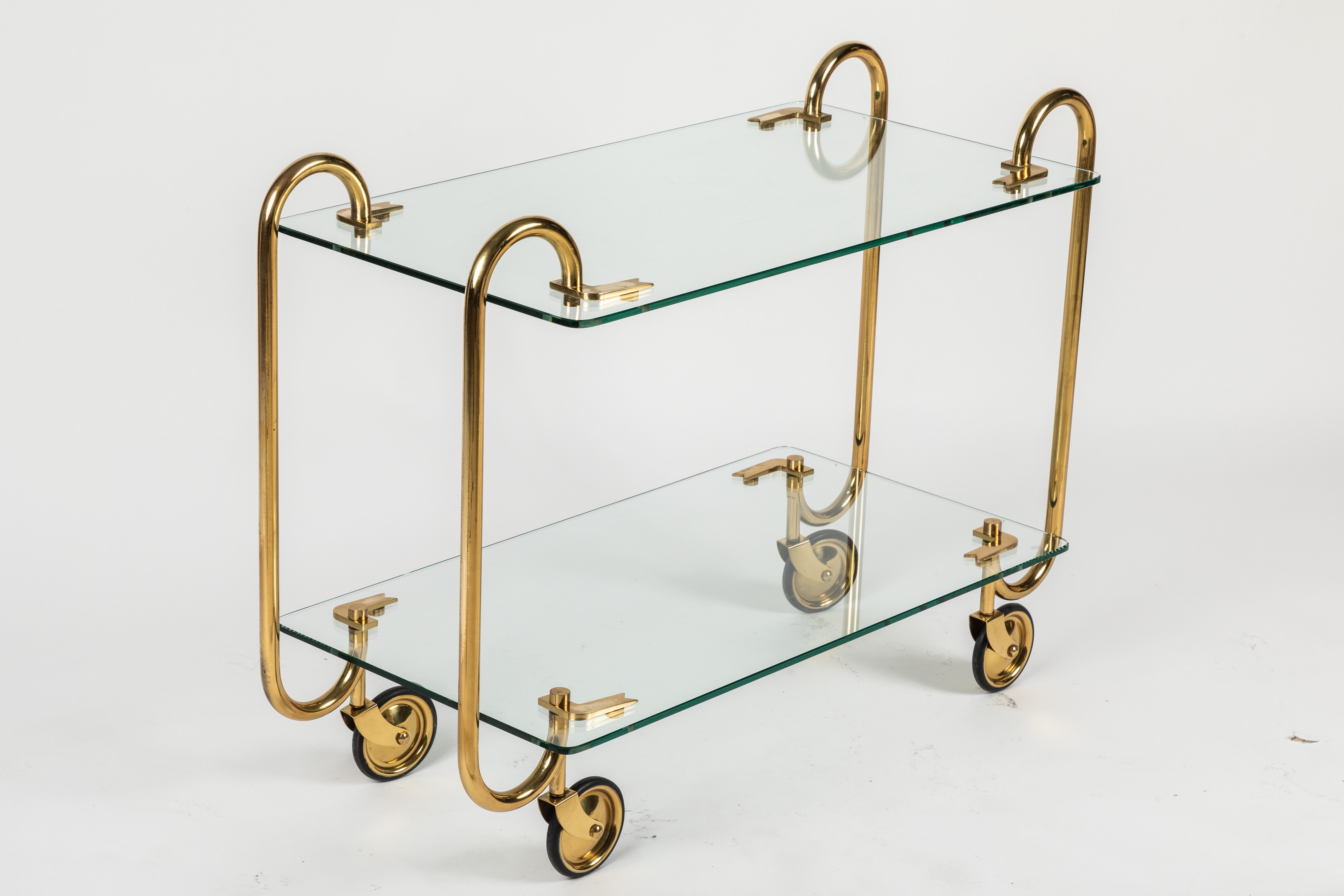 Iconic brass and glass drinks trolley designed and made by Italian powerhouse Fontana Arte. This classic design is made with tempered glass upper and lowers shelves and 4 brass structures ending in brass wheels.
Glass is in perfect condition and