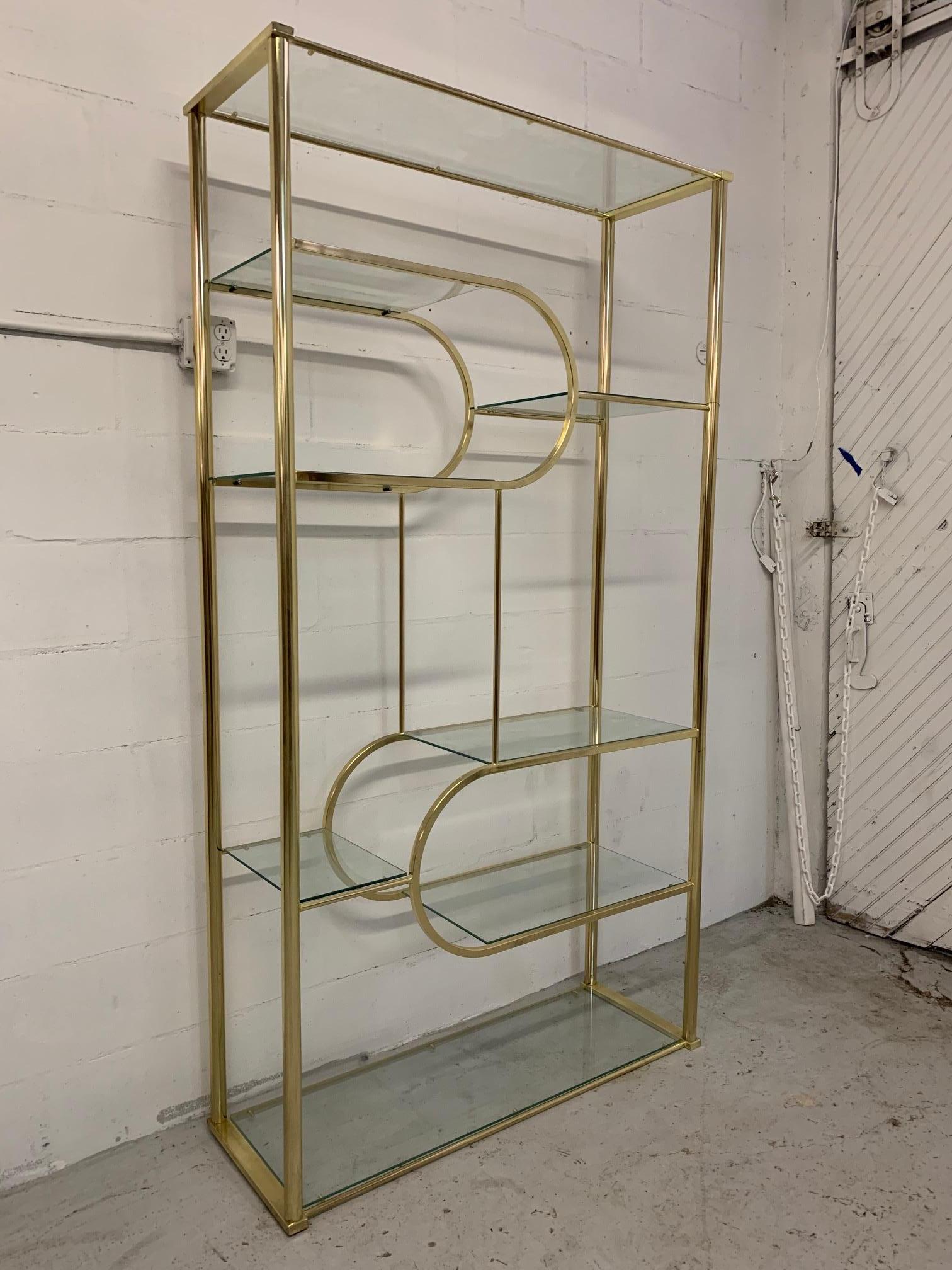 Brass and glass étagère by DIA in the manner of Milo Baughman features glass shelving and a unique design. Good condition with only minor imperfections consistent with age.
