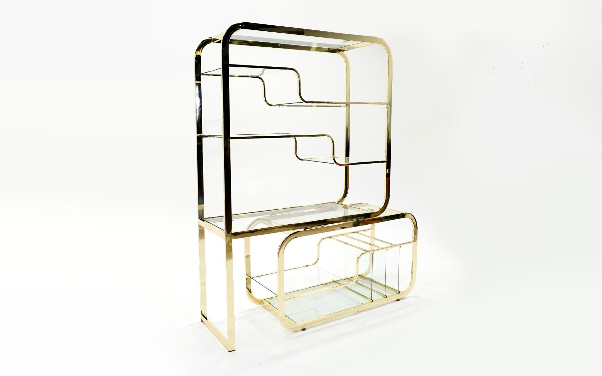 Expandable brass étagère with glass shelves and vertical record album / book storage. Often attributed to Milo Baughman, 1970s. The brass is bright and in very good condition. One vertical piece of glass has a small corner chip not visible until