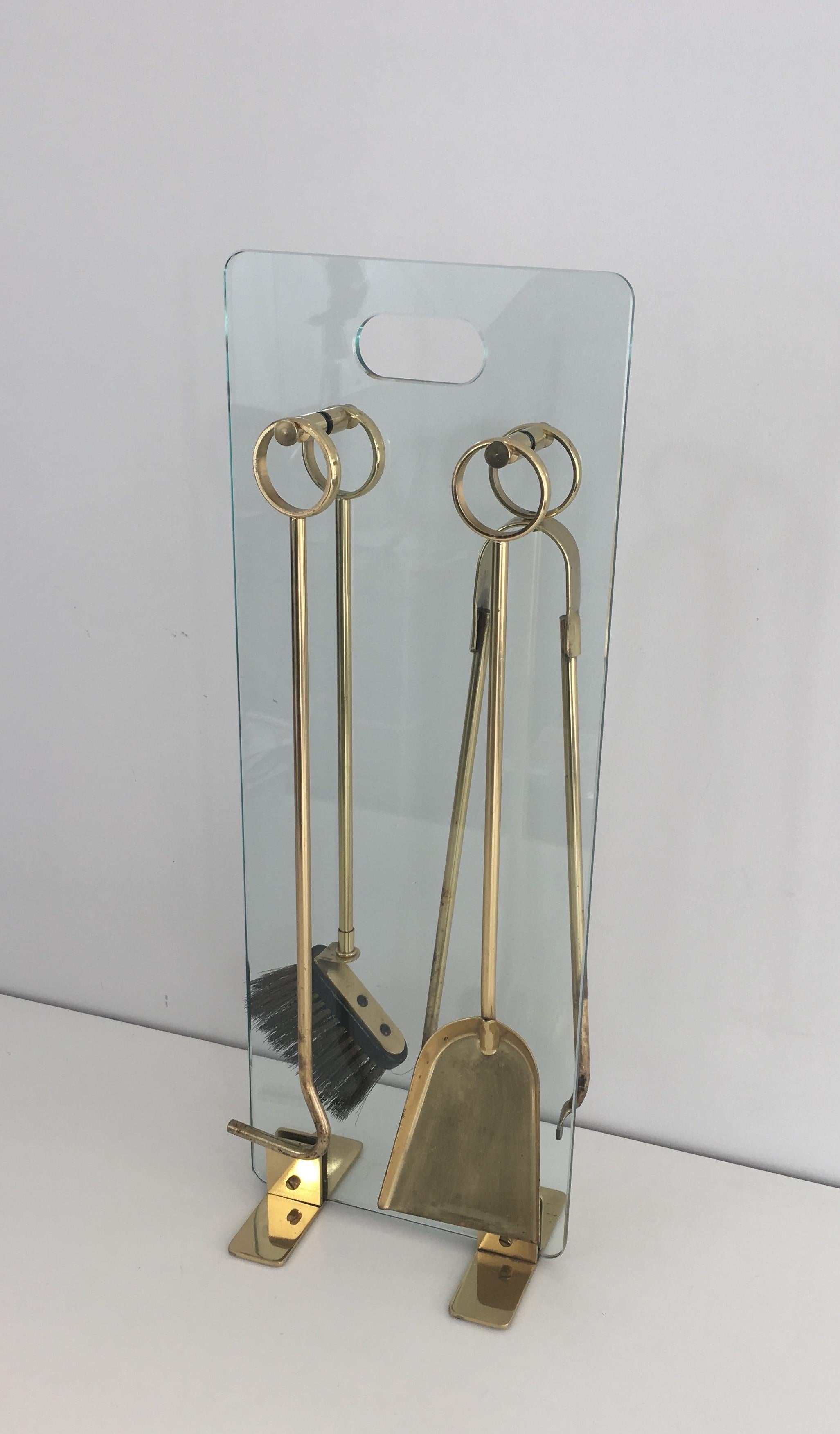 This fire place tools are made of brass on a brass and tempered glass stand. Thids is a French work, circa 1970.