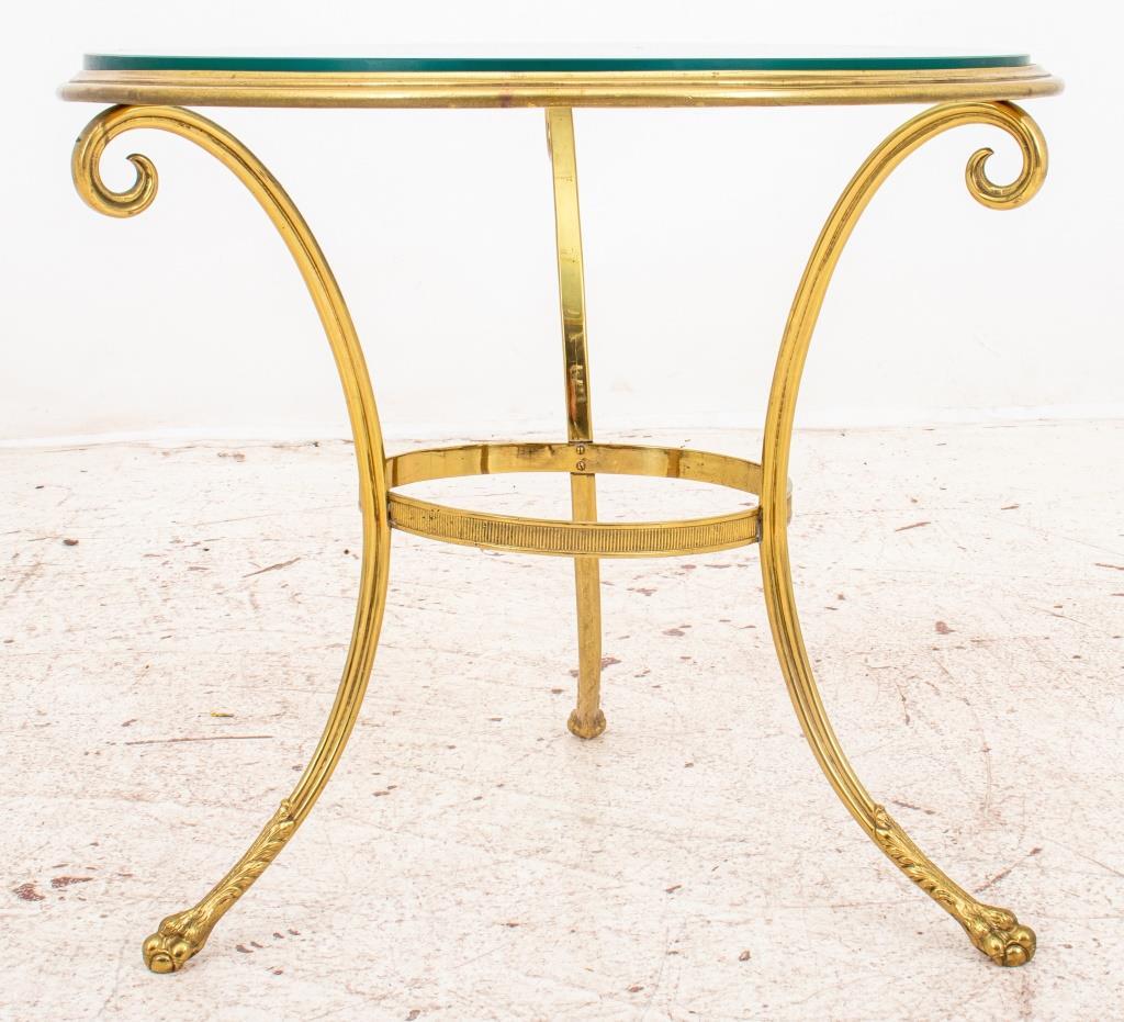 Brass and glass gueridon table, with circular glass top on tripodal base with scrolling legs conjoined by a circular stretcher, and terminating in lions' paw feet.

Dealer: S138XX