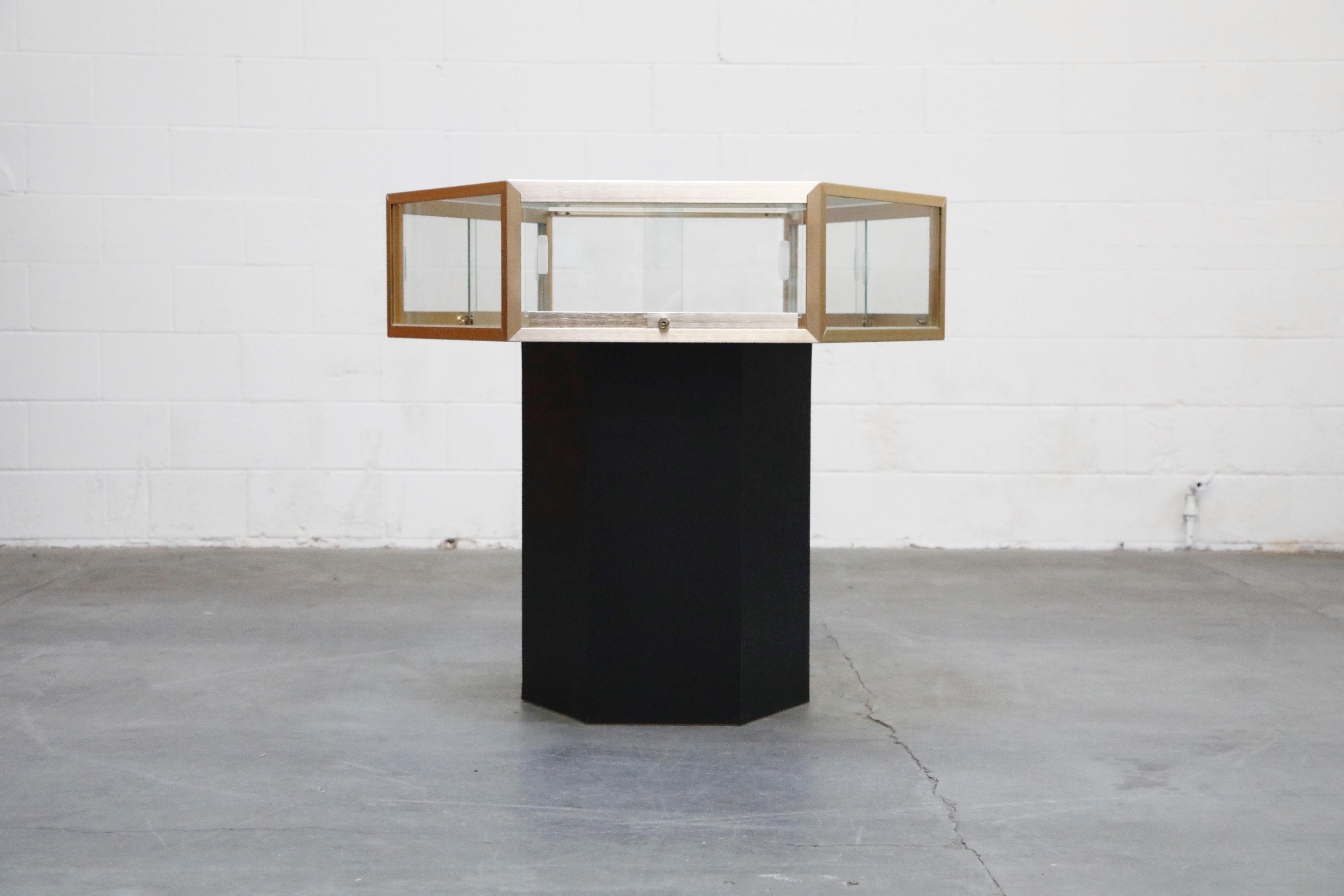 This fantastic 1970s modern hexagonal display case features a floating center table top that also functions as a lockable display enclosure. On a black pedestal base and black interior, the display case top is wrapped in 6 panels of glass with a