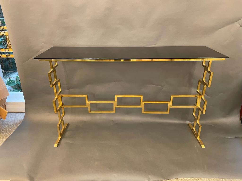 The console has a minimalist structure design, composed of a structure of squares in brass tube in two dimensions. The top is made of an elegant black mirrored glass. Italy, circa 1980s.