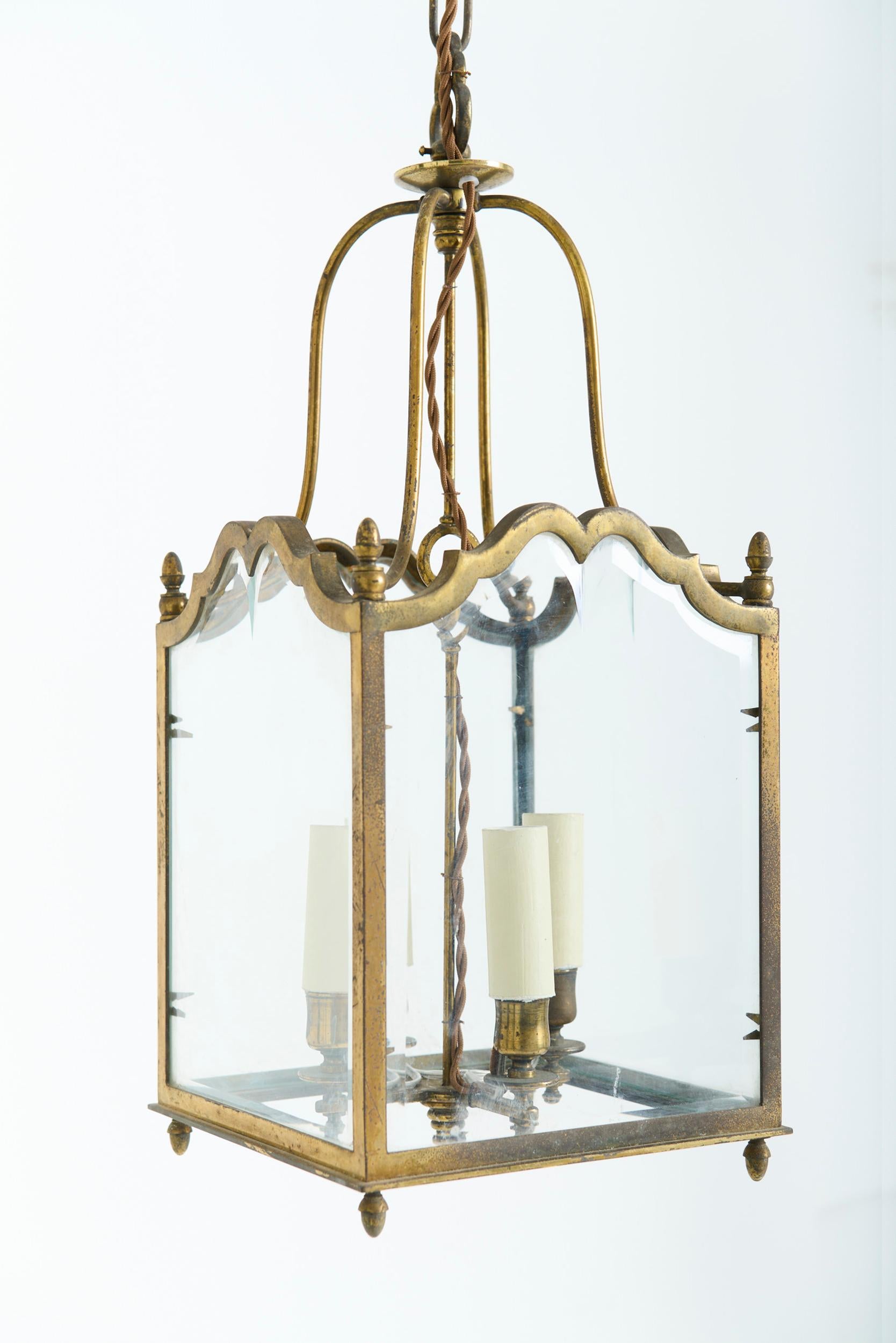 A brass and bevelled glass lantern
Italy, Circa 1940
50 cm high by 20 cm wide by 20 cm depth
Ceiling dome: 14 cm 
Chain: 26 cm