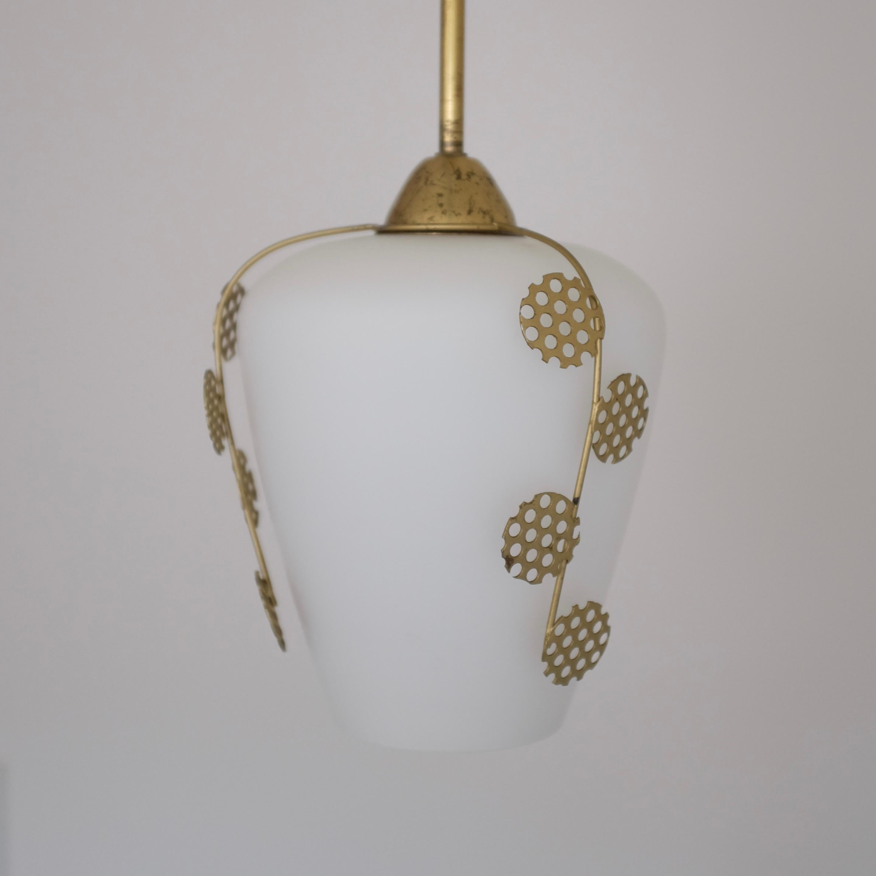 Swedish Modern light pendant with beautiful leaf ornament in brass and white frosted glass. Three decorative leaf ornaments stretches down the side of the glass lantern. Straight lamp arm and canopy in brass with age appropriate wear. There is a