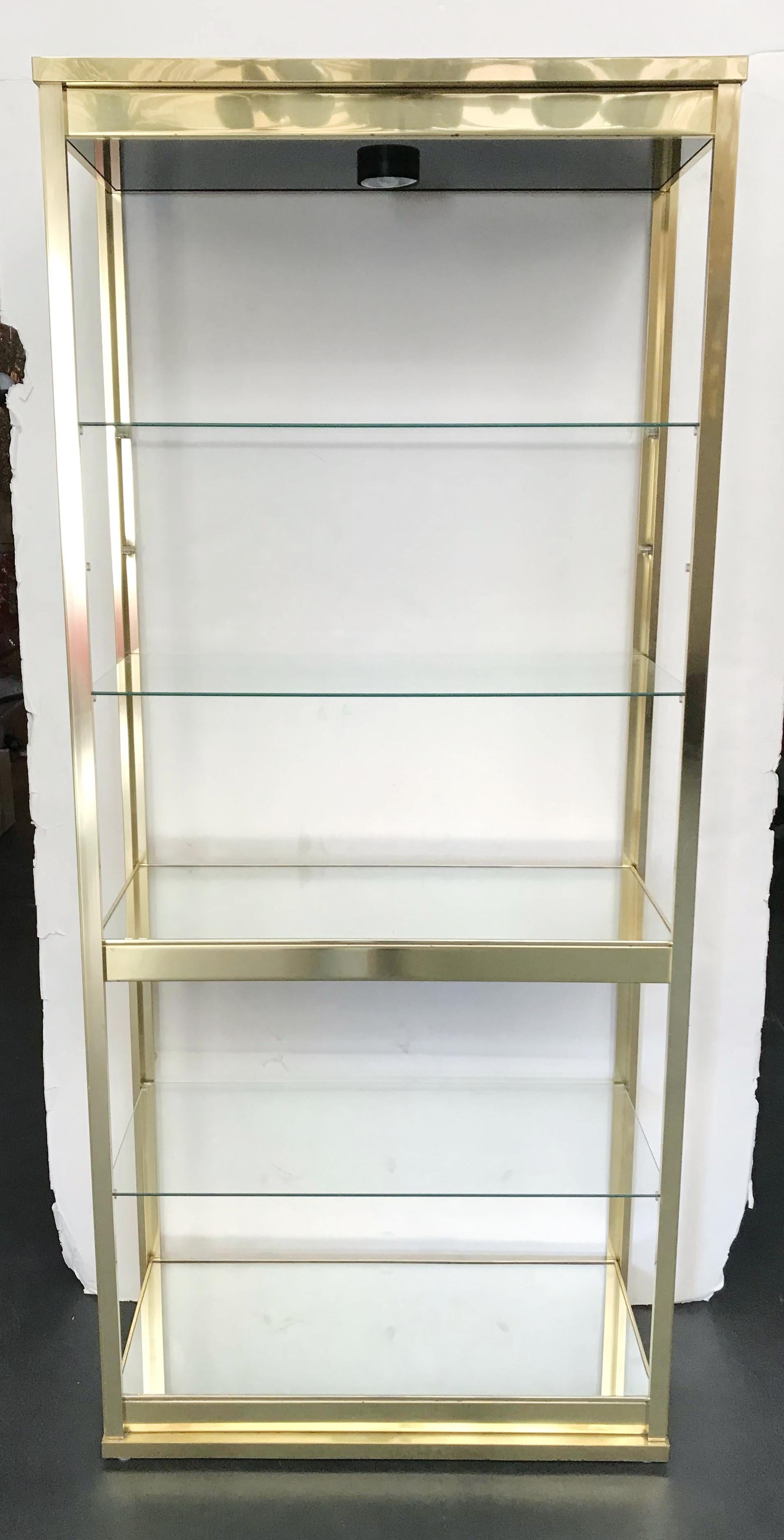 Stunning midcentury vintage étagère in excellent condition, satin brass finish frame with three clear glass shelves and two mirrored shelves, can be illuminated with one light on top, made in the USA, circa 1970s
Measures: Width 33 inches, depth 15