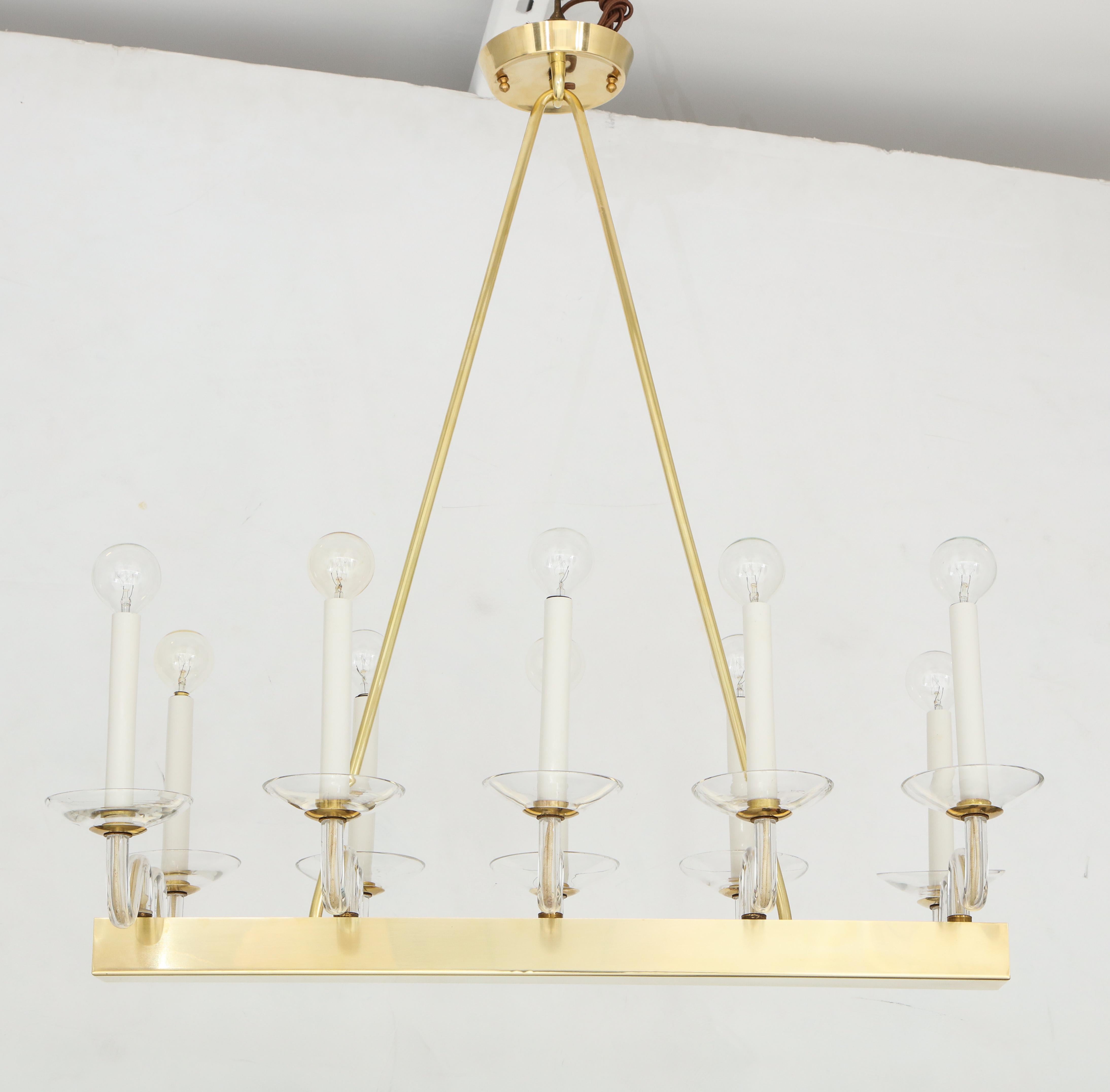 Elegant brass and glass midcentury chandelier
The Minimalist polished brass frame holds ten clear glass arm and bobeches
that have been newly rewired with candelabra sockets.
The fixture is stamped Germany.