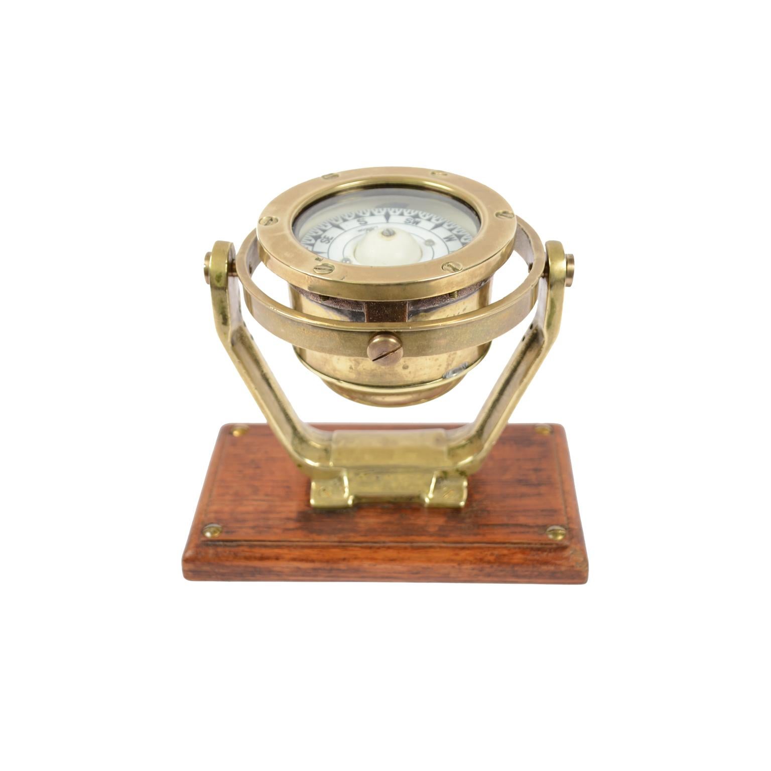 Brass and glass nautical compass on universal joint signed Coubro & Scrutton Ltd London from the second half of the 19th century and mounted on oak wooden board. The compass consists of a brass and glass vessel on the bottom of which is fixed a
