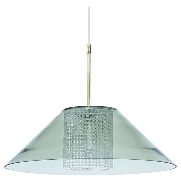 Pendant lamp designed by Carl Fagerlund for glass company Orrefors. Manufactured in Sweden during the 1960s. Outer cup in clear grey tinted glass with a cylindrical internal diffuser in clear pressed glass. Polished brass fittings. New electricity.