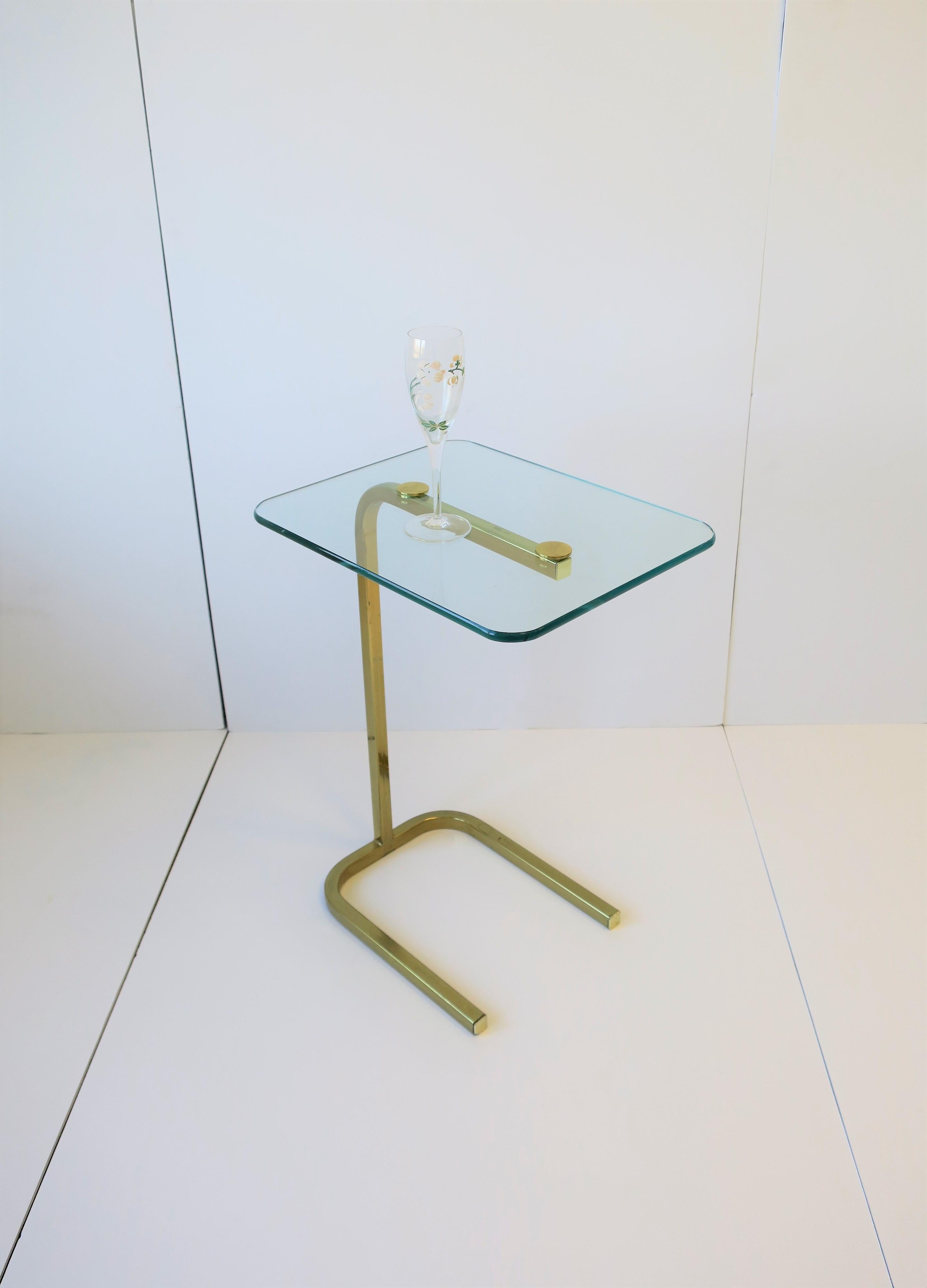 A rectangular brass and glass side or drinks table in the Modern style, circa late 20th century. Table's glass top is rectangle in shape with rounded corners and a brass metal plate frame. Table's design is in the style of the Pace Collection of