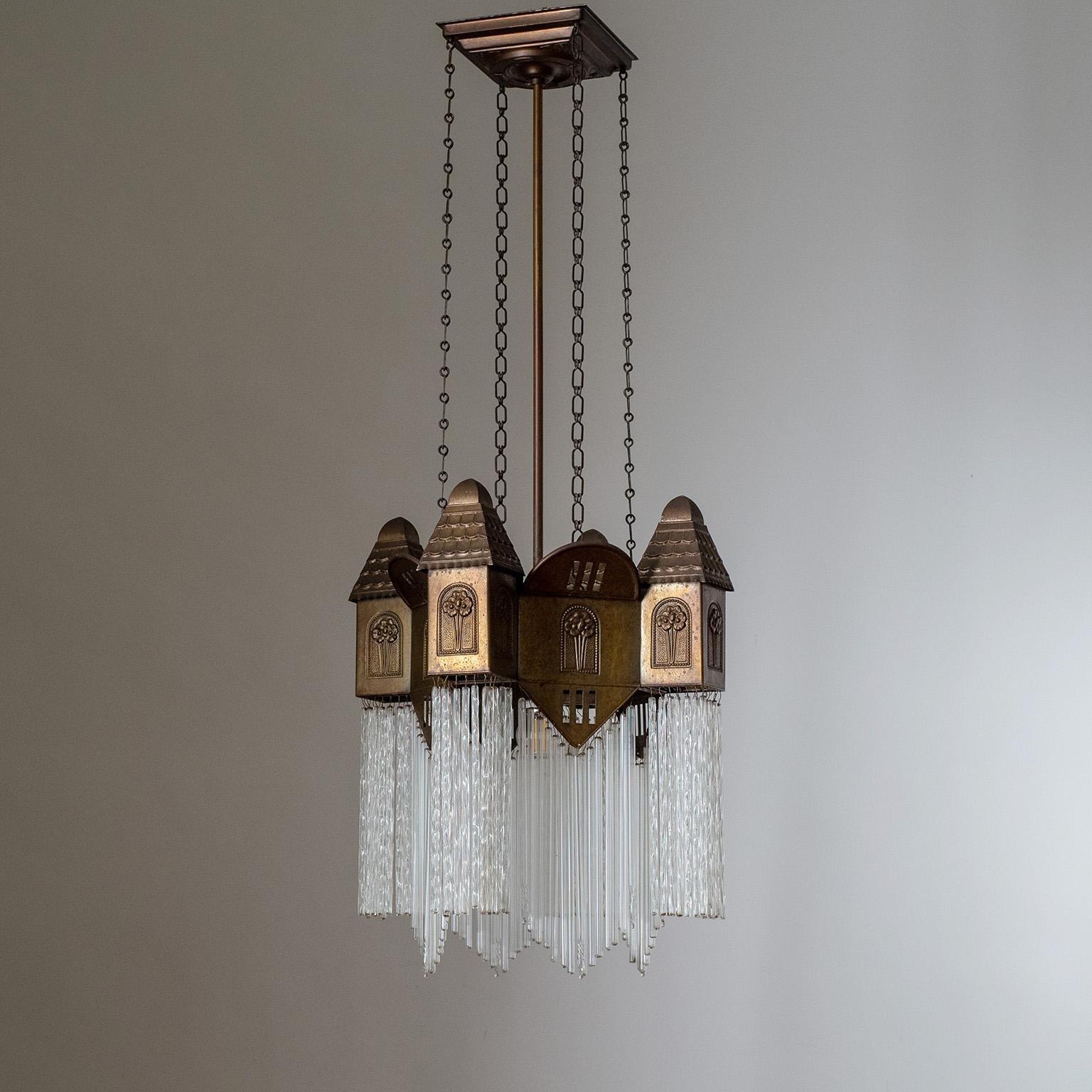 Rare Arts & Crafts suspension light from the early 20th century. Charming architectural body made of embossed sheet brass with three different types of glass rods. One original brass and ceramic E27 socket with new wiring.
Measures: Height 93cm