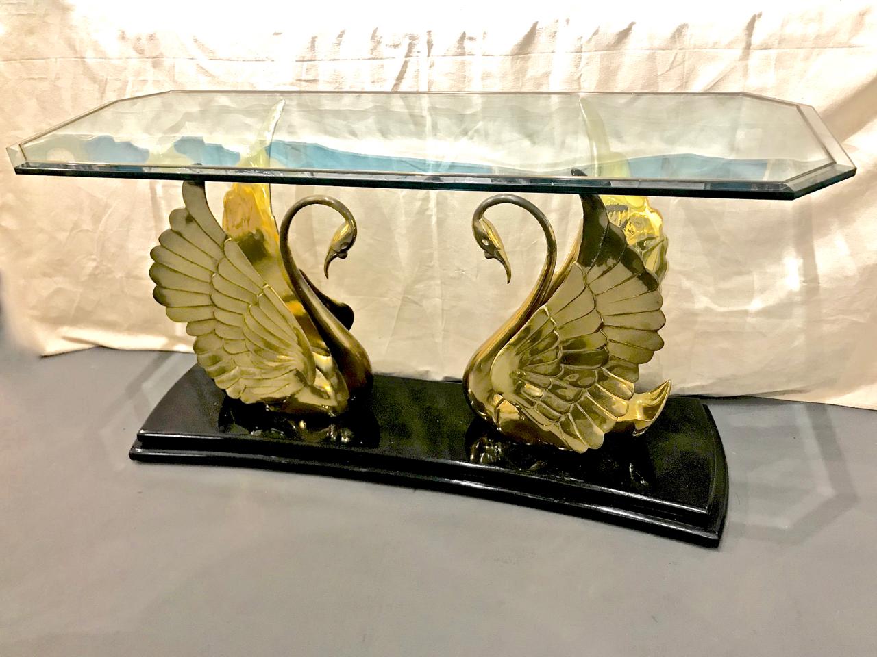 This is a stunning moderne-style solid brass swan and glass console table mounted on a substantial black lacquered plinth. The quality level of this console is of the highest, note the superb inlay of the brass rod into the thick beveled glass top.
