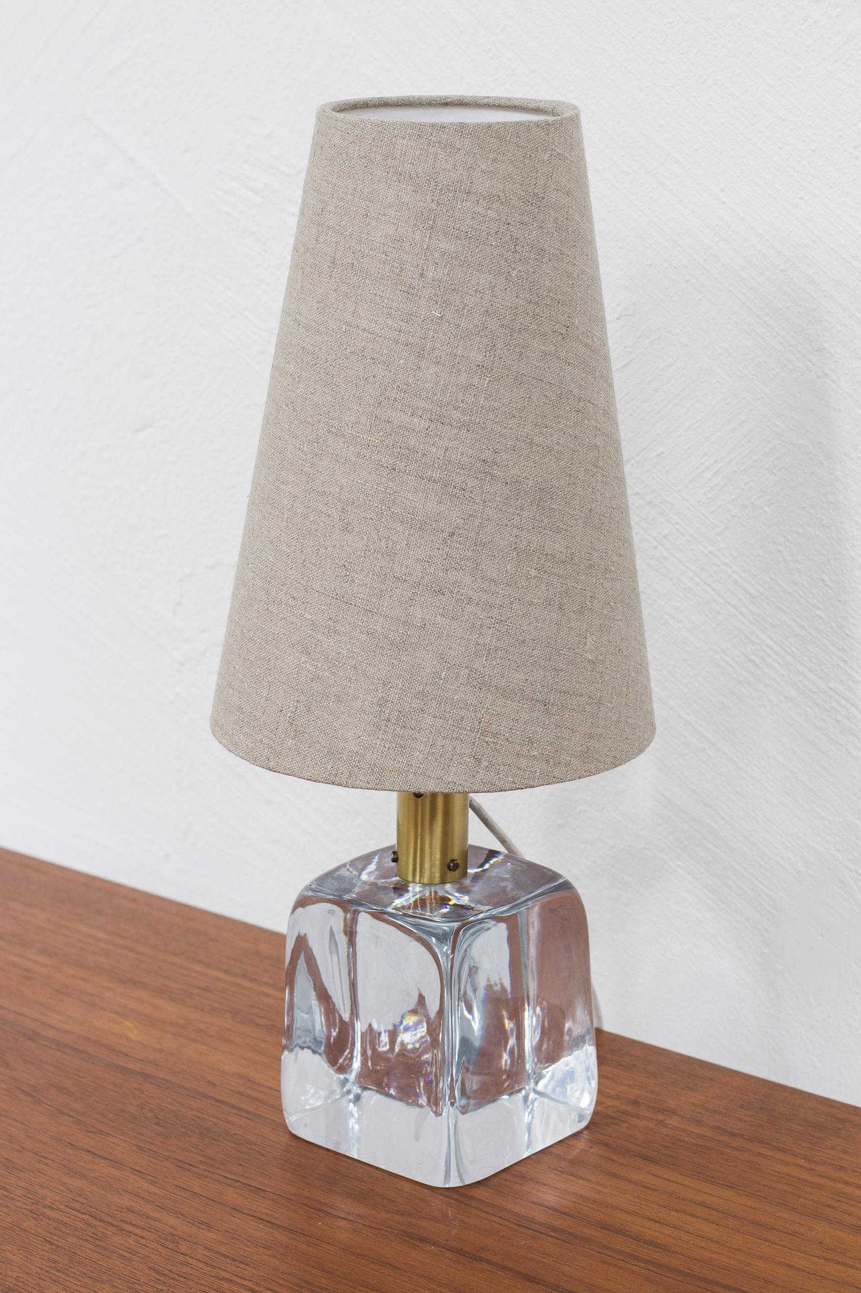 Table lamp model 1819 designed by Josef Frank. Produced by Svenskt Tenn in Sweden during the 1950-60s. Made from blown clear glass and brass. New linen lamp shade in grey. Very good vintage condition with few signs of age related wear and