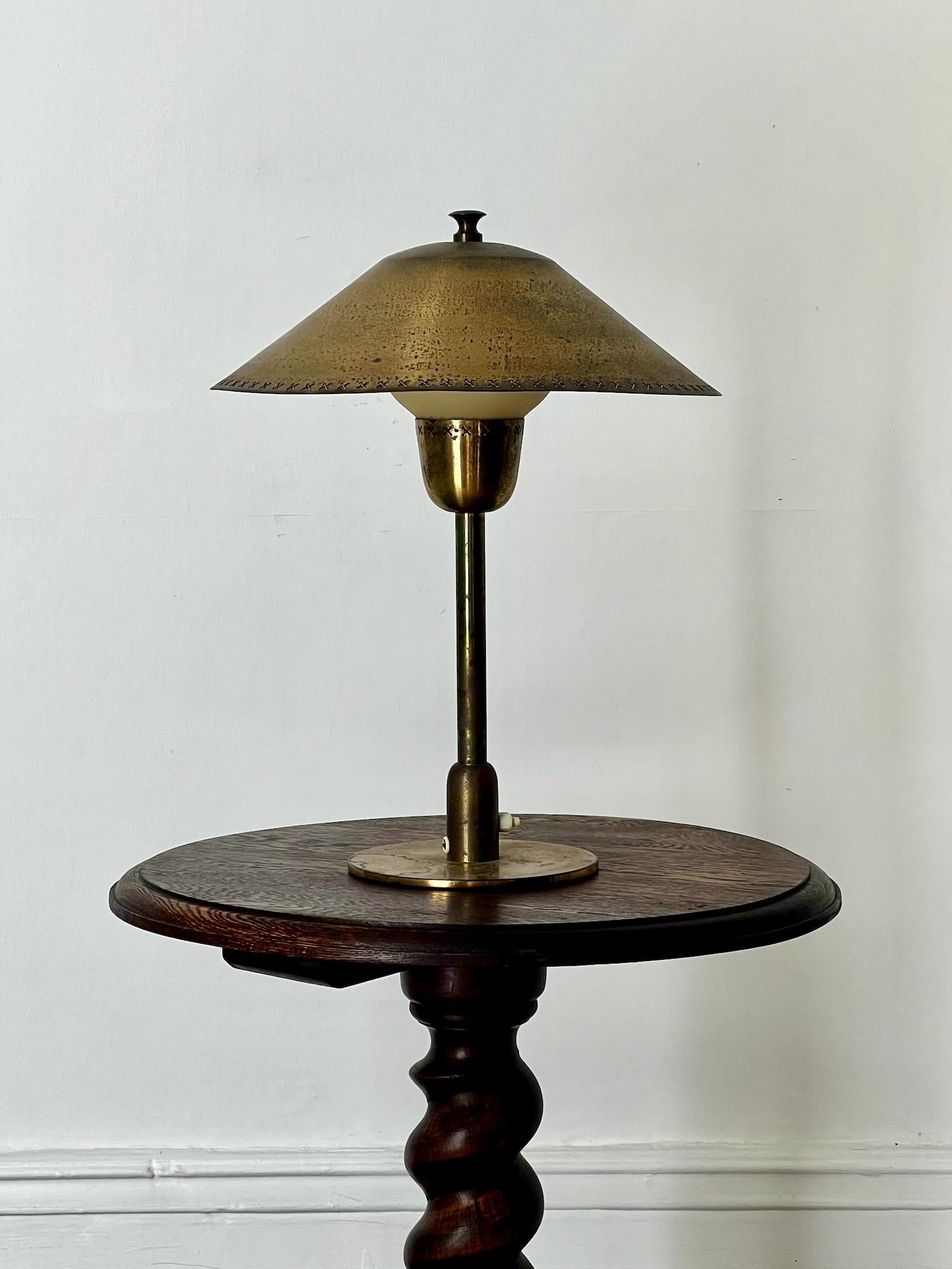 A brass and glass table lamp with pretty pierced details to the shade. Attributed to Bent Karlby for Lyfa of Denmark, 1940s or 1950s.

A simple design with a wide brass shade and simple brass stem and base; the pierced shade fits over a diffuser of
