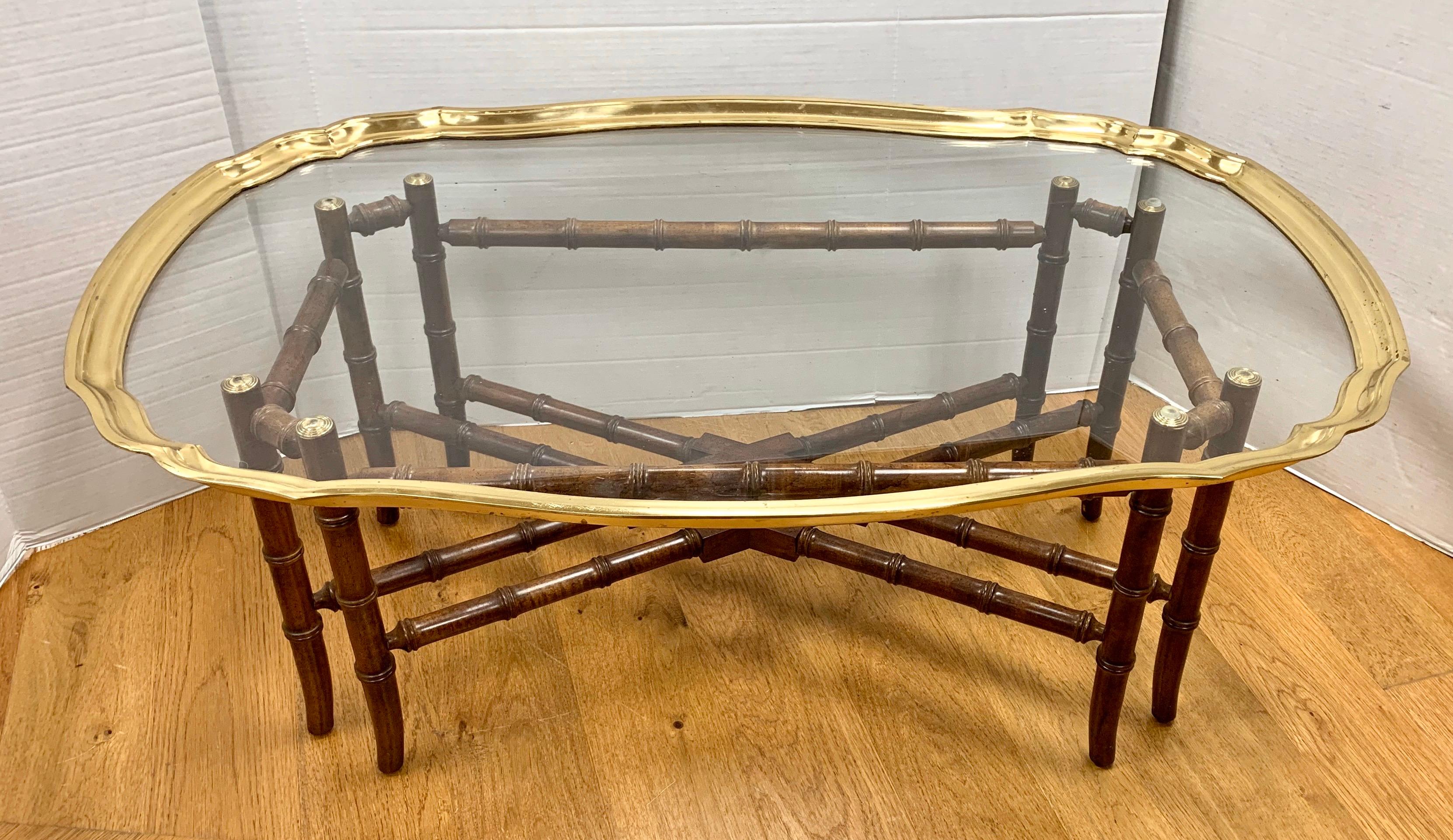 Vintage brass and glass tray top with scalloped rim sits atop a carved faux bamboo wood base. Base is constructed of stained wood and does not collapse. Brass and glass top is removable.  Made by Baker Furniture.