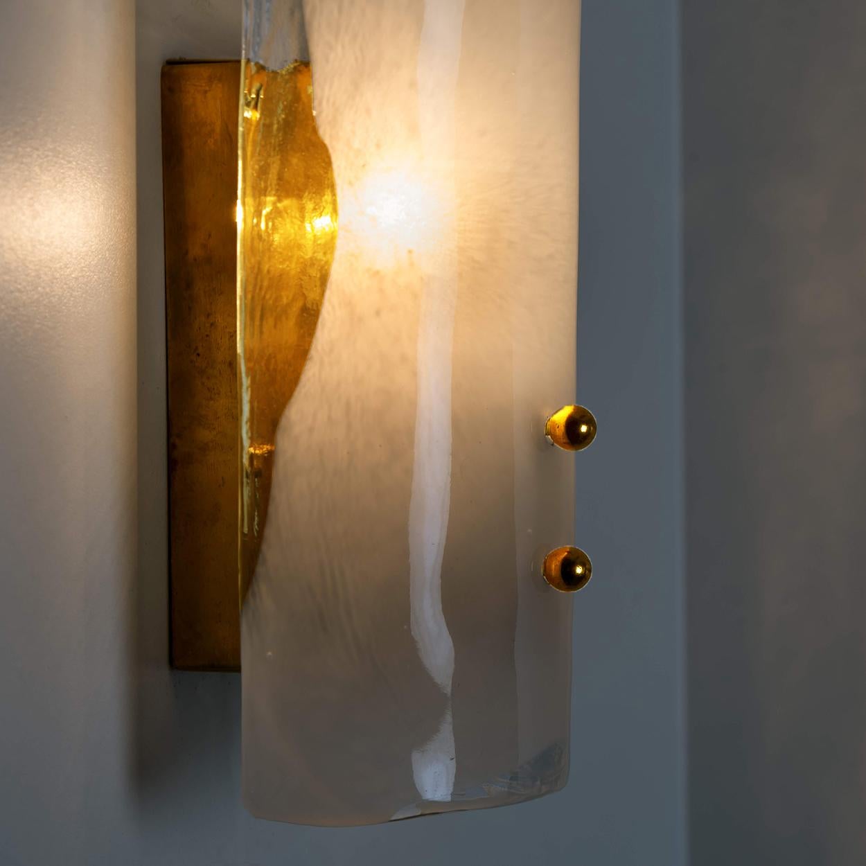 Apliques de pared de alta gama fabricados en cristal de Murano soplado transparente y opalino sobre un herraje desordenado. Diseñado y producido por J.T. Kalmar, Austria, en la década de 1960. Diseño minimalista ejecutado con gusto por la excelencia