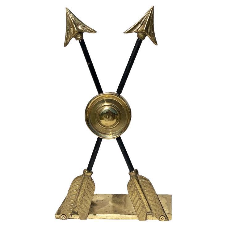 A beautiful pair of brass arrow bookends. Created from solid brass, this pair features a brass medallion bullseye which is intersected by two arrows. The arrows are black iron-looking, but solid brass in the middle. The arrow tips are brass, with