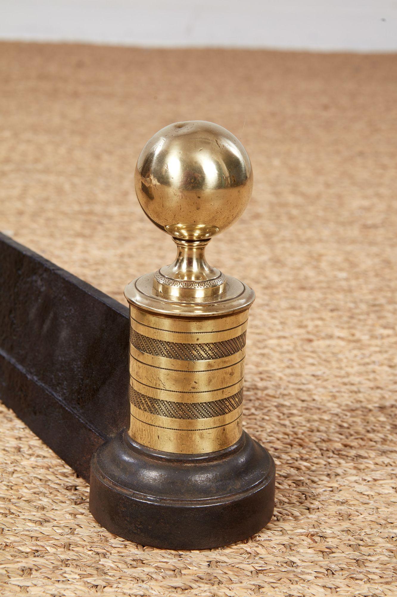 A handsome pair of early 19th century brass andirons or log rests with ball finials over finely etched 