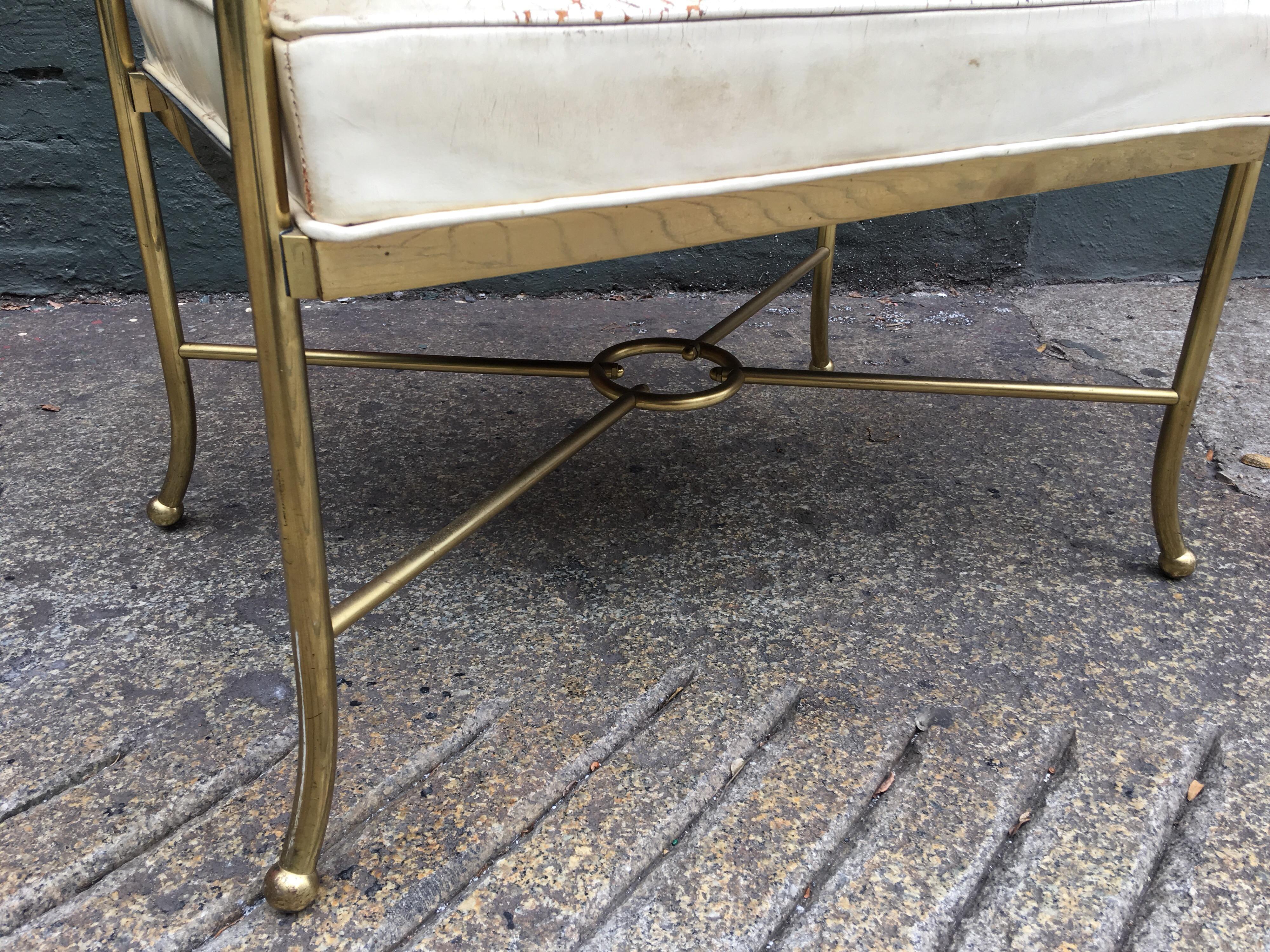 1950s brass and leather bench with original cream leather. All new foam has been replaced on seat cushion while preserving the patina of the leather. Brass stretchers with center circle.