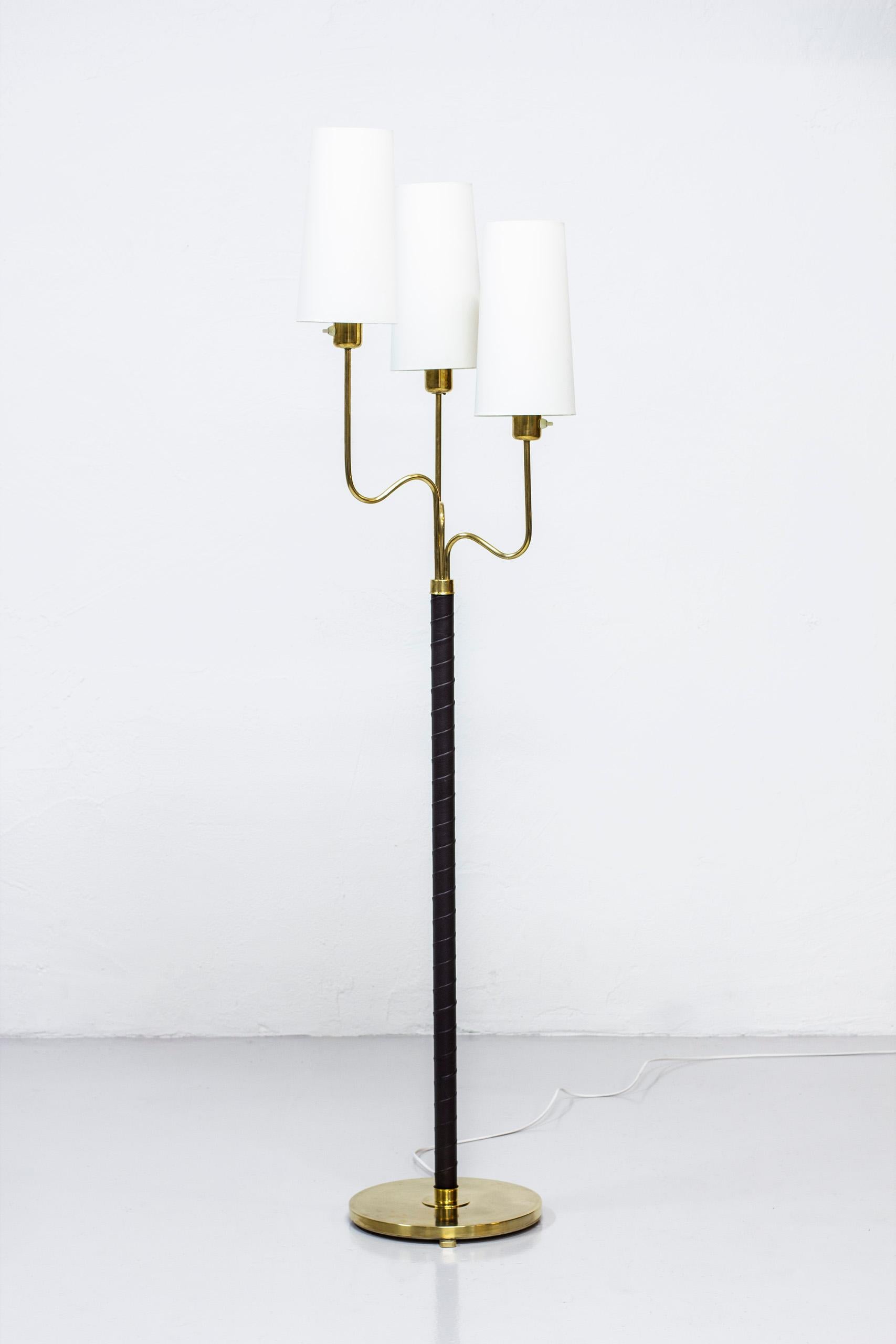 Floor lamp designed by Hans Bergström. Produced by ASEA in Sweden during the 1940s. Polished brass, aubergine/dark brown leather and chintz fabric shades. Light switches on each lamp in working order. Very good vintage condition with some signs of