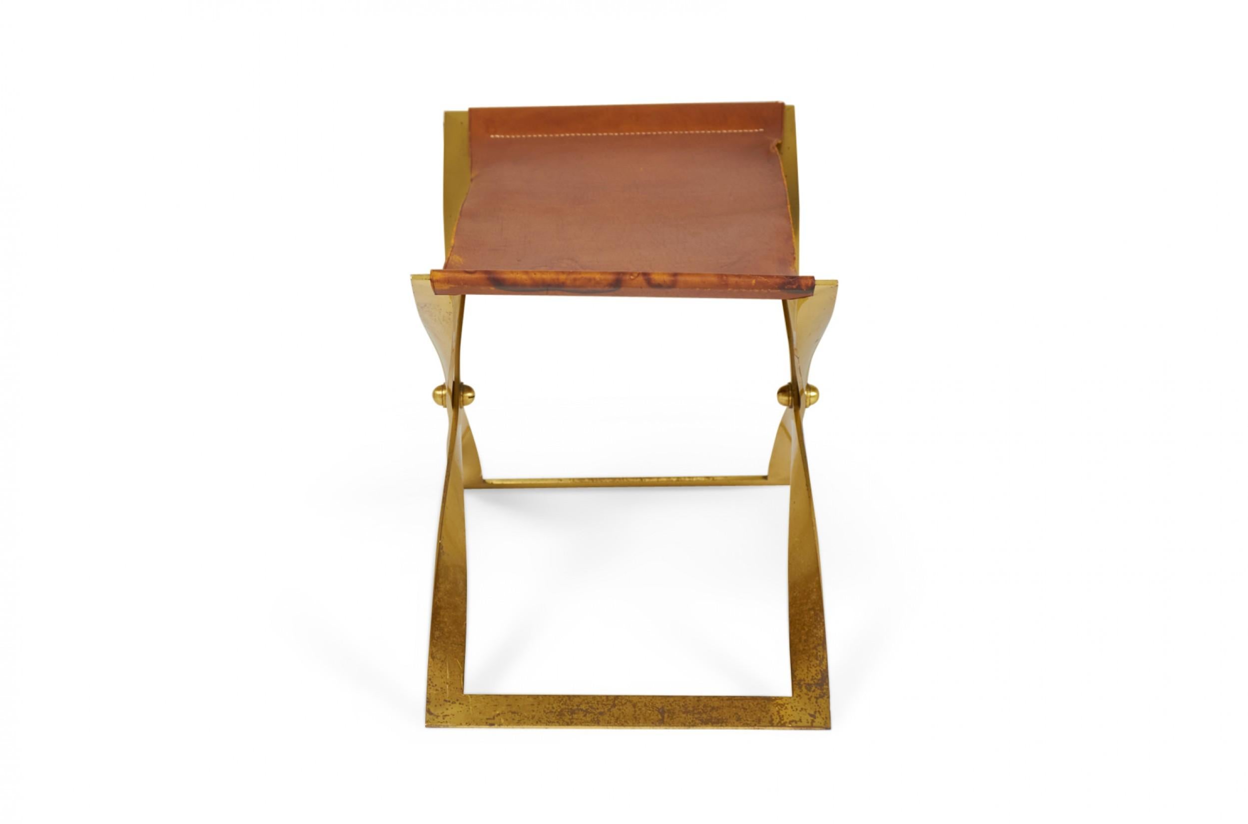 American Mid-Century scissor bench with a polished brass x-shaped frame and a brown leather sling seat.