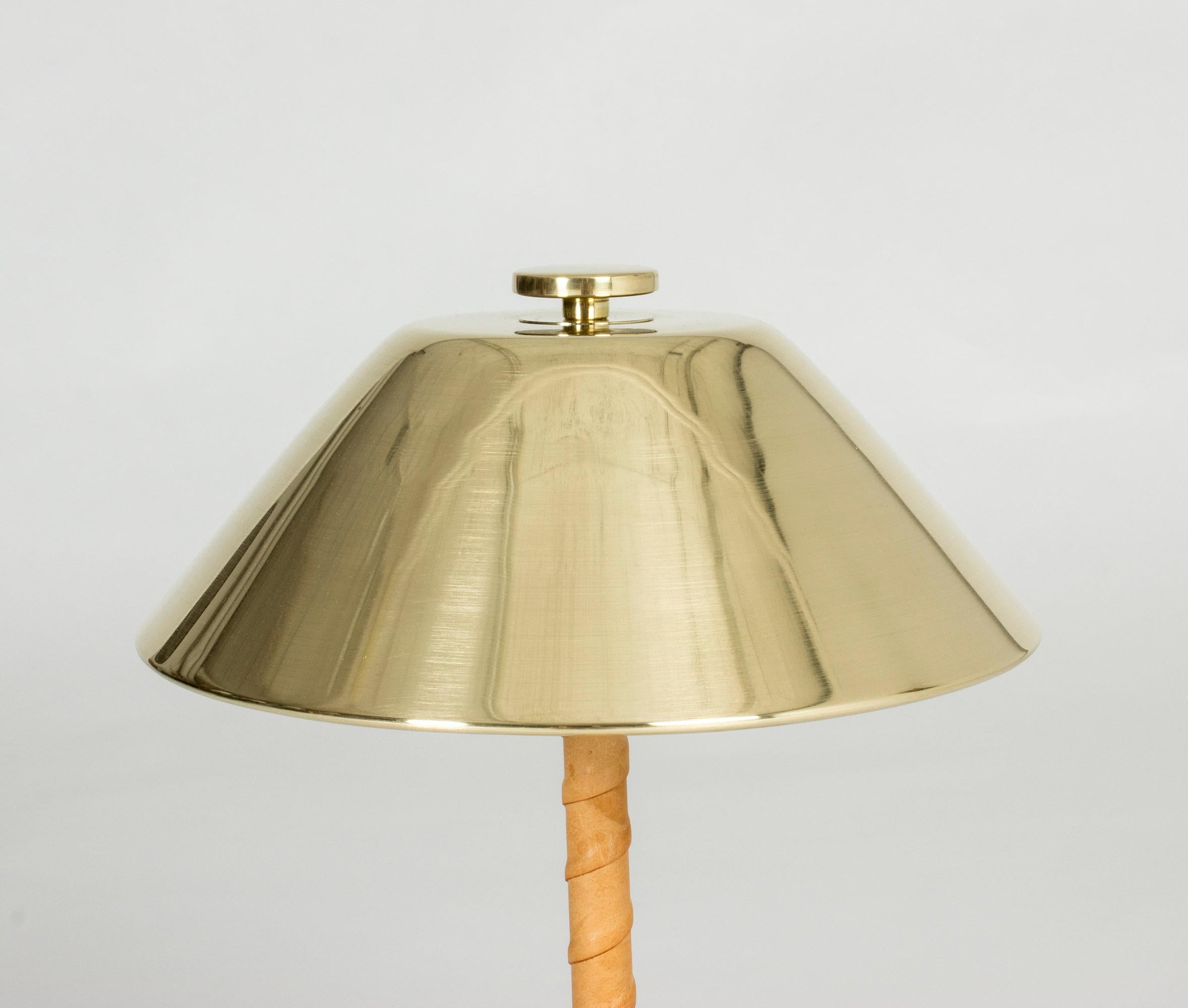 Very elegant table lamp by Einar Bäckström, made from brass with an appealing, disc decoration on top and handle wound with nude leather.