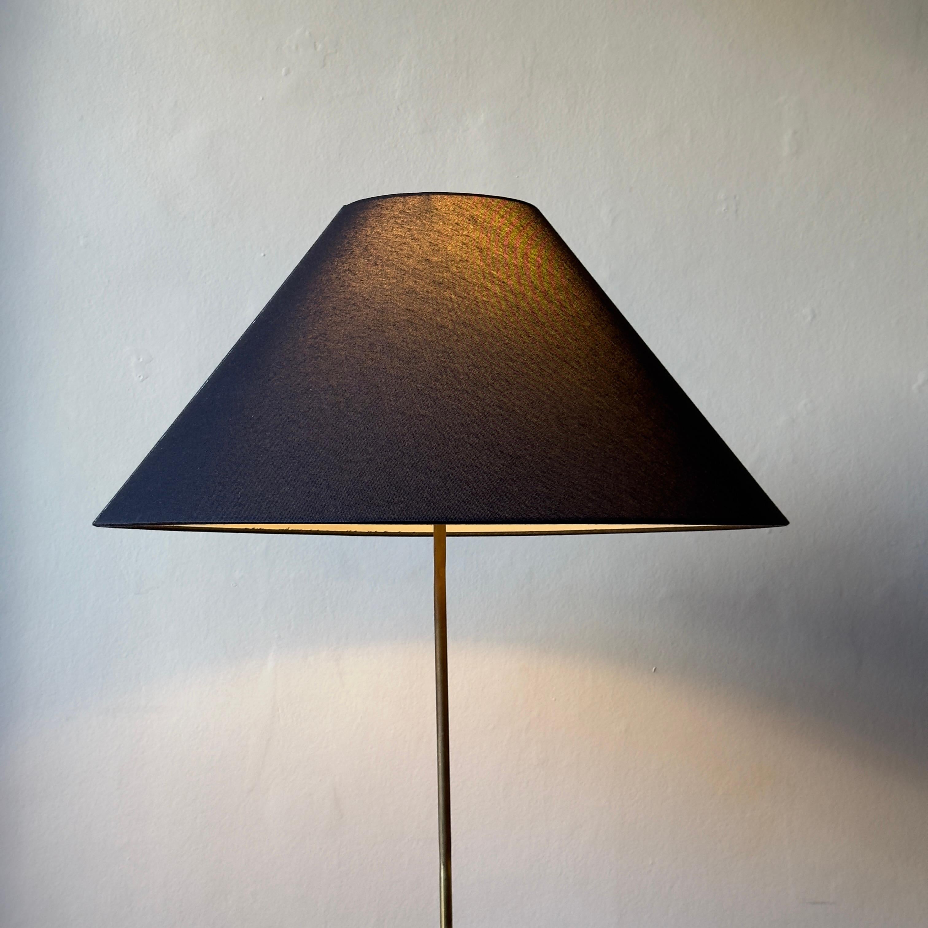 A leather bound, brass, telescopic floor lamp with conical, navy shade. 

This floor lamp was produced in Denmark during the 1950s. The base and upper stem of the lamp display an even, purple-brown hued patina. The lower portion of the lamp has been