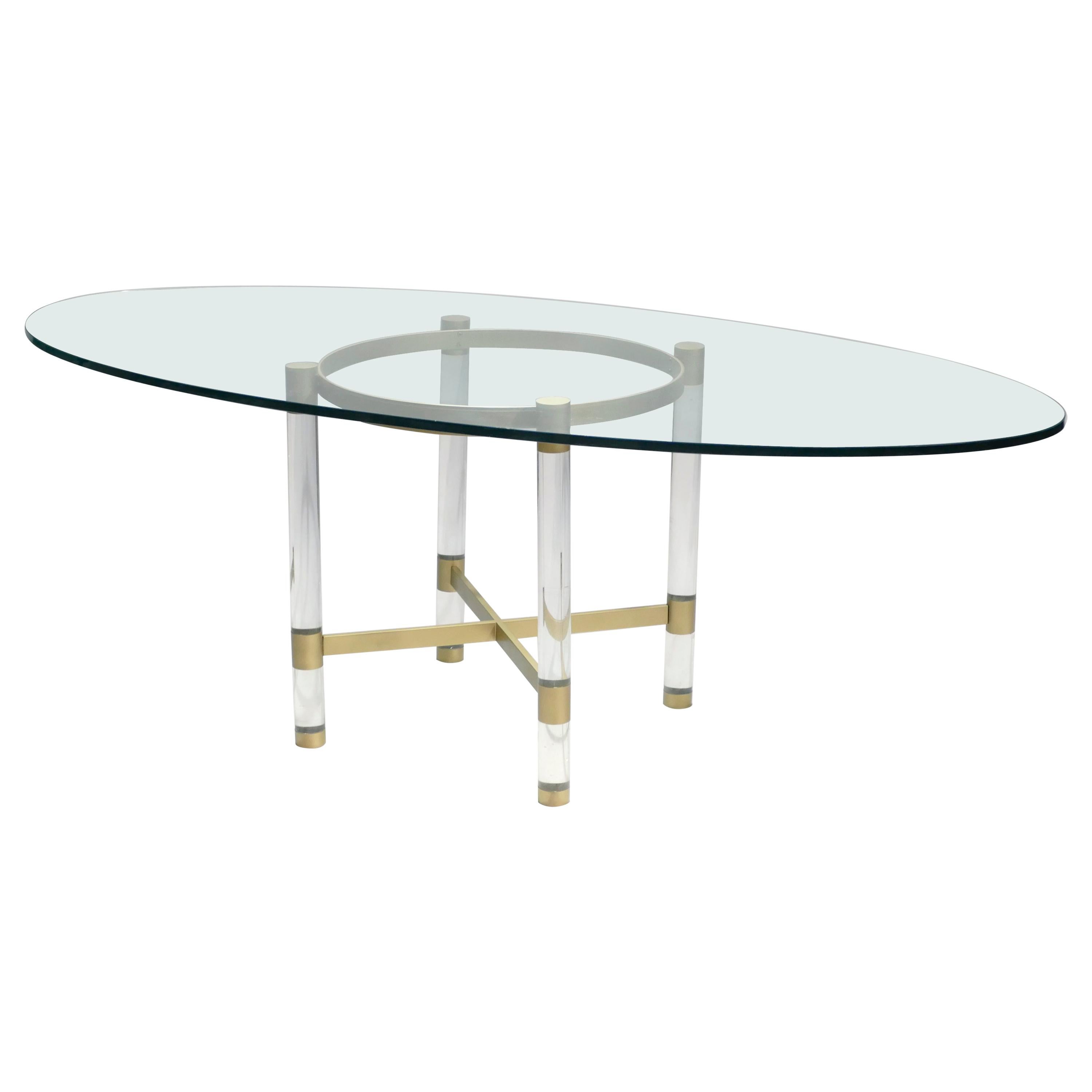 A rare find, this dining table exemplifies the designs by Sandro Petti for company Metalarte around 1970. A thick transparent glass surface has a striking oblong shape and rests atop Lucite and matte brass legs. Four Lucite columns support a brass