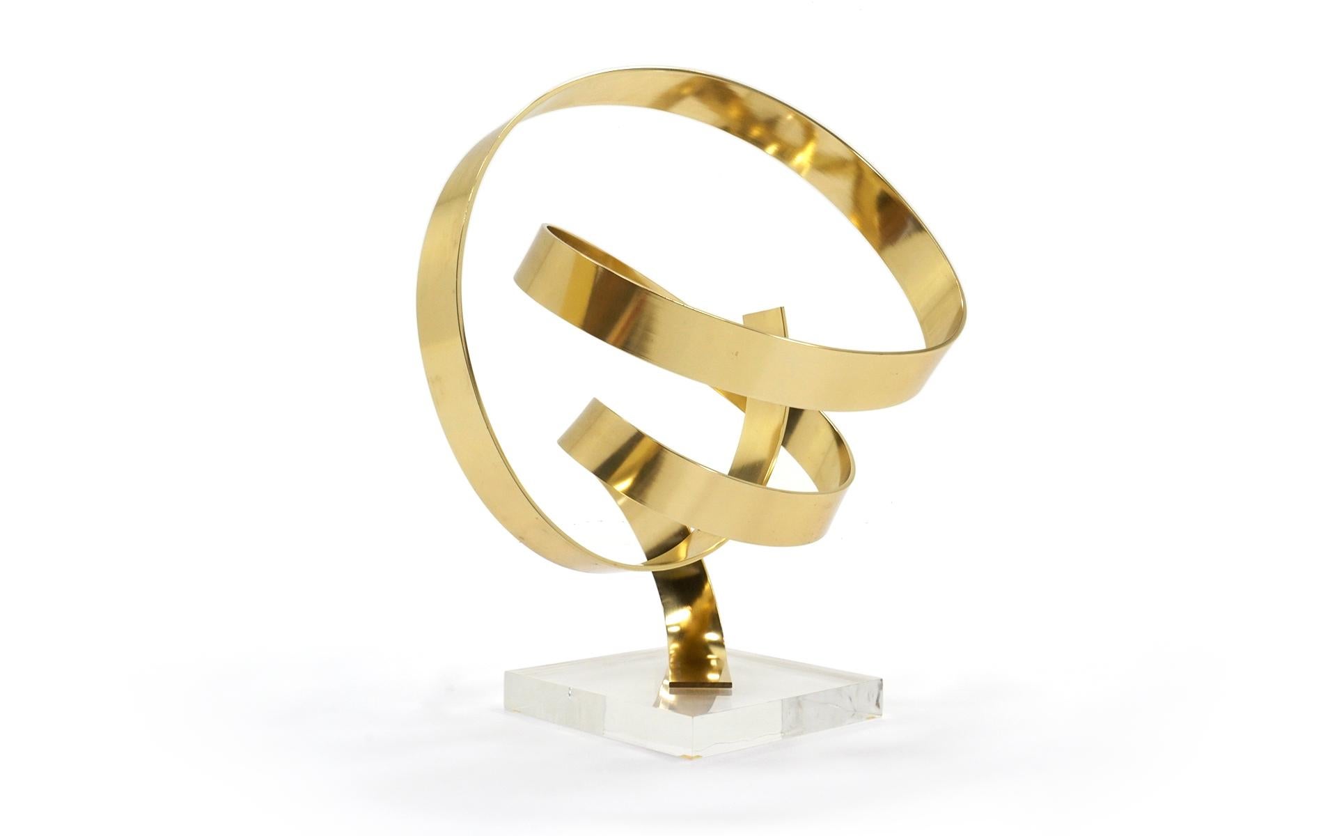 Ribbon tabletop sculpture by artist Dan Murphy. Brass freeform design on acrylic base.