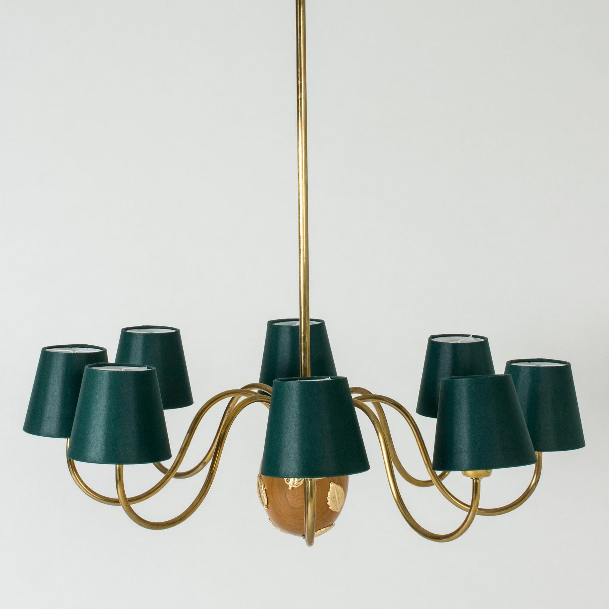 Vivacious brass chandelier with eight arms by Hans Bergström. The center of the chandelier is an acorn-shaped mahogany piece, decorated with beautiful brass leaves.
