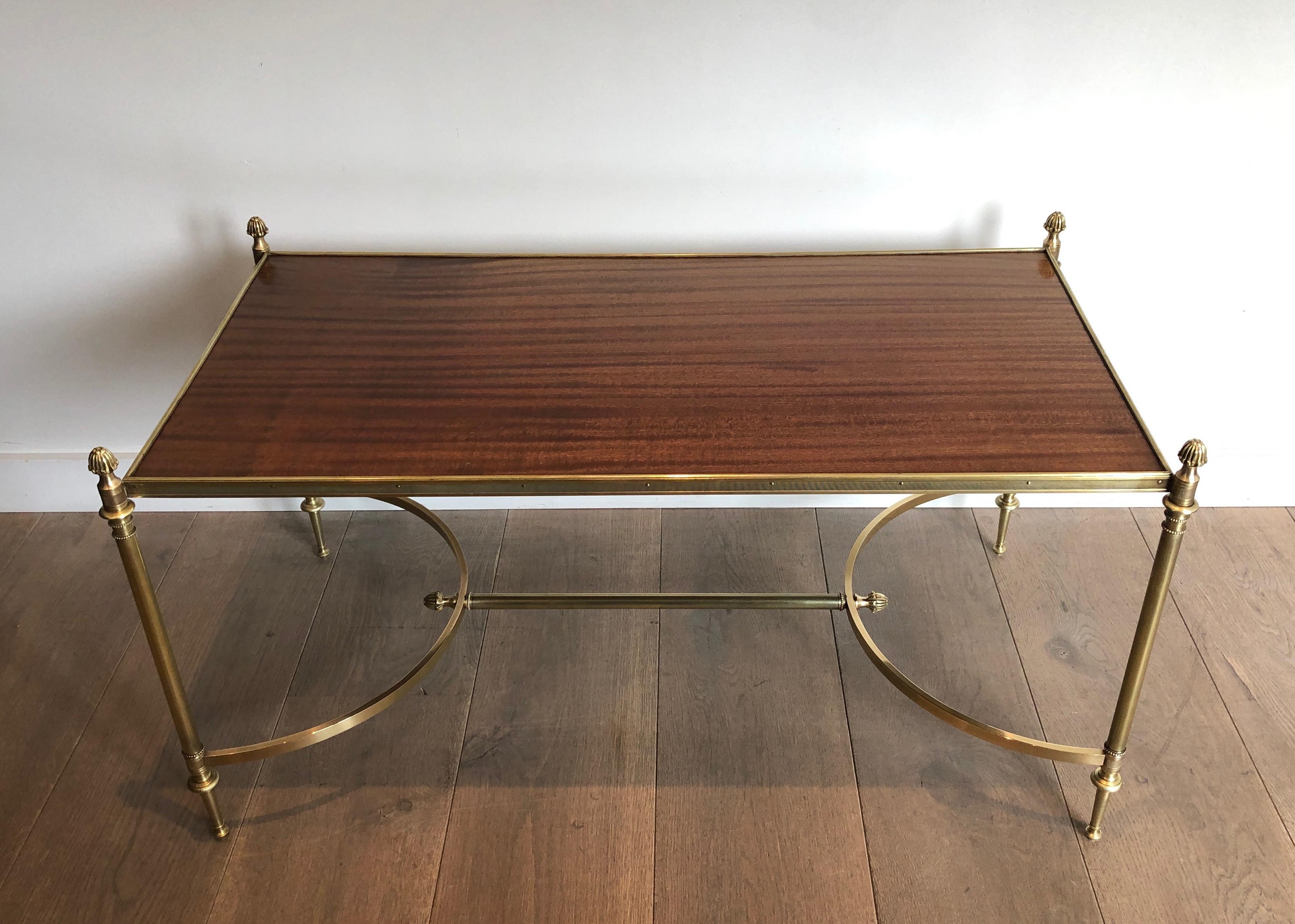 This neoclassical style coffee table is made of brass with a mahogany top. This is a French work by Maison Jansen. Circa 1940.
