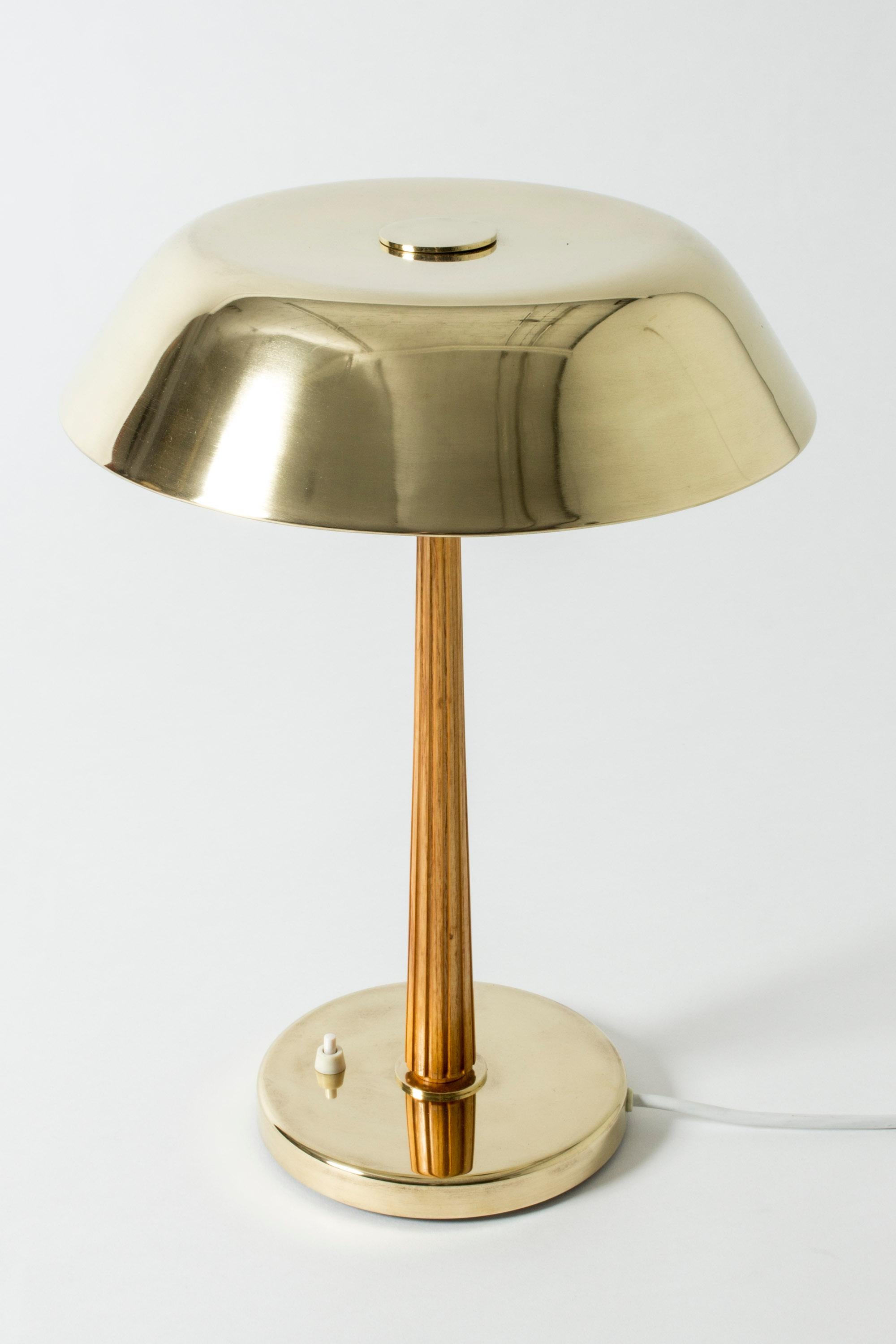Elegant brass table lamp from Böhlmarks, with a smoothly rounded shade. Shade adorned with a sphere on top. Mahogany handle with embossed stripes.