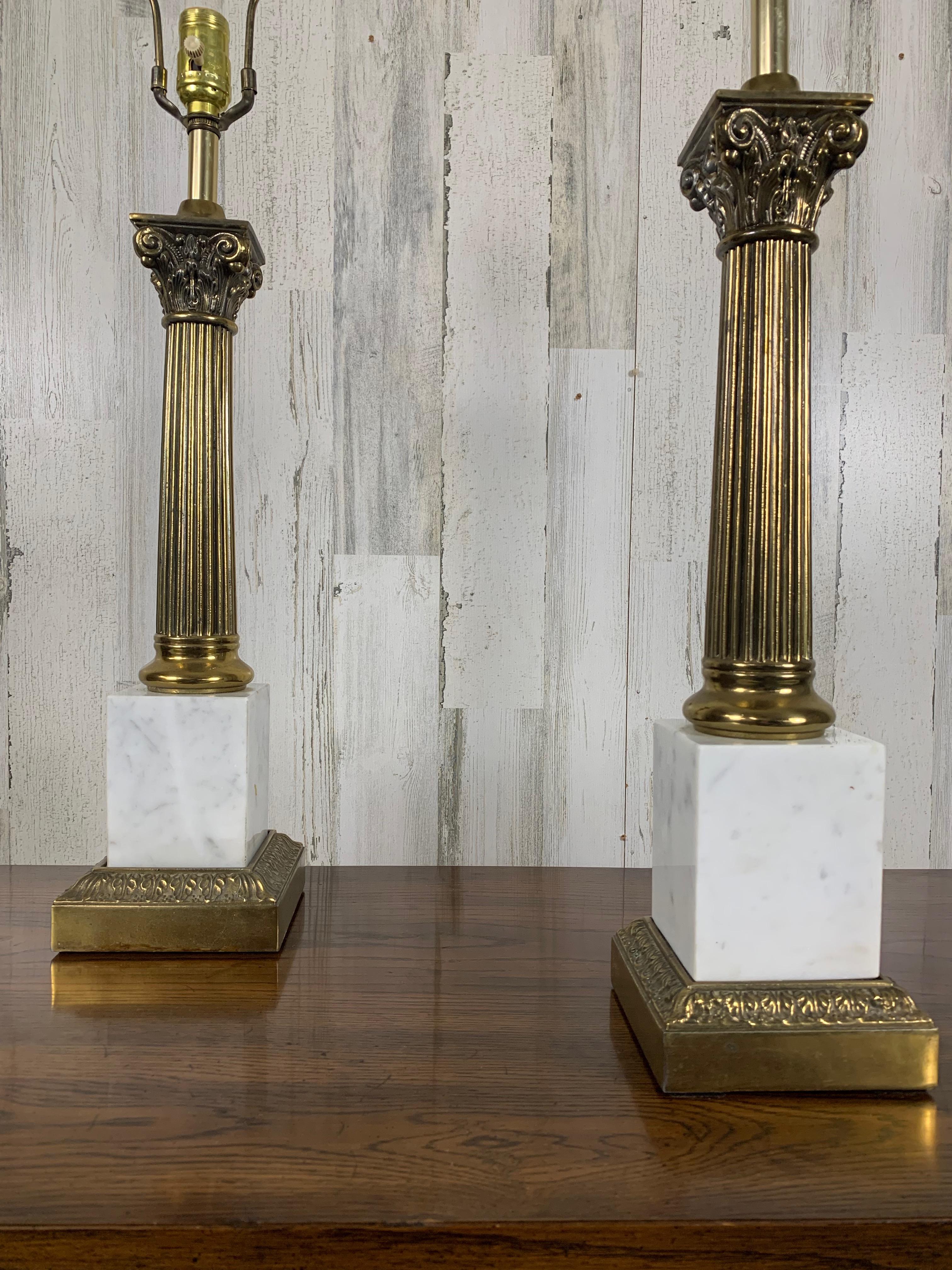 Pair of classical style Table lamps consisting of fluted brass columns with Corinthian capitals and white marble plinth. perfect for that library or living room.
Made by Westwood Industries. The pleated shades are not included. 
31.75