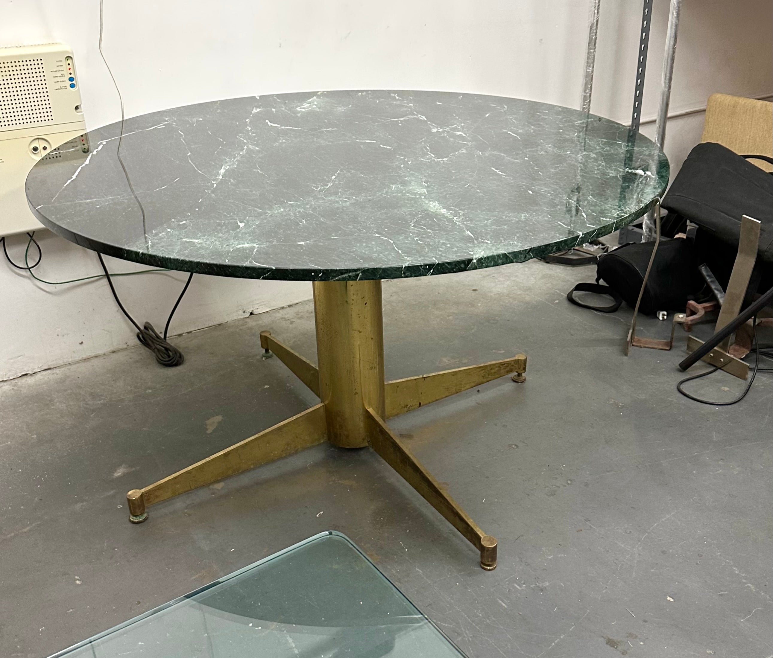 Handsome architectural dining or center table. 1” thick green marble top on a solid brass support with adjustable leveling feet. Super high build quality 