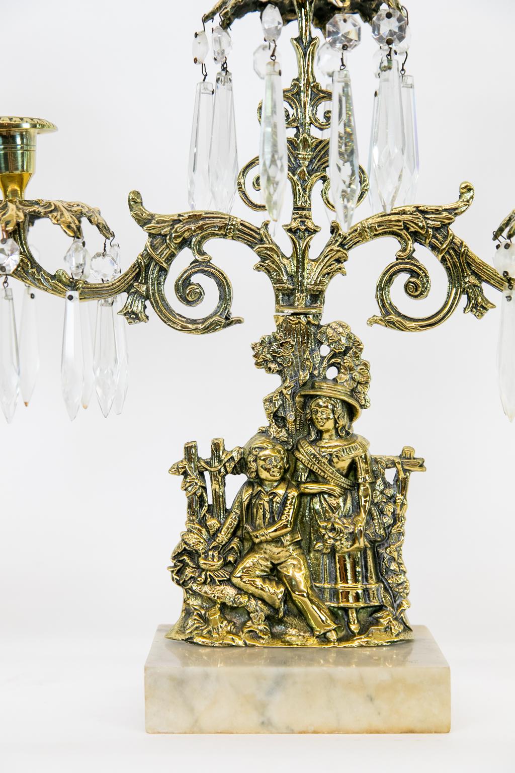 Brass and marble girandoles, each formed with floral arabesques as well as women and child figures on marble bases. The prisms are cut glass. The middle girandole is 15” wide, they are 5.5” wide at the base.