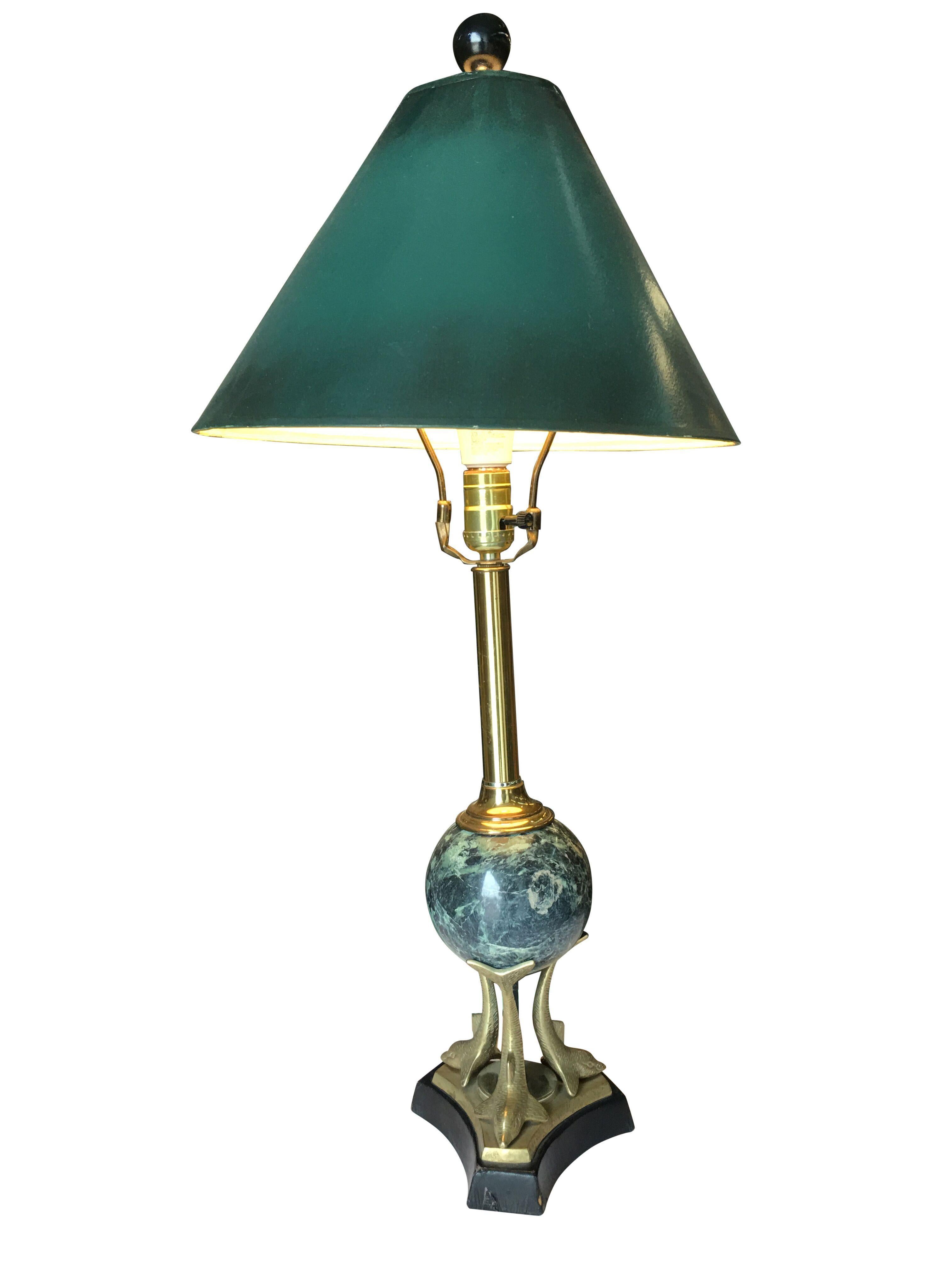 Vintage brass and marble sculptural dolphin table lamp pair. Each lamp features a green banker style shade with a sculptural lamp with a leather-wrapped wood base with a trio of brass dolphins holding up a green marble ball connected to a brass