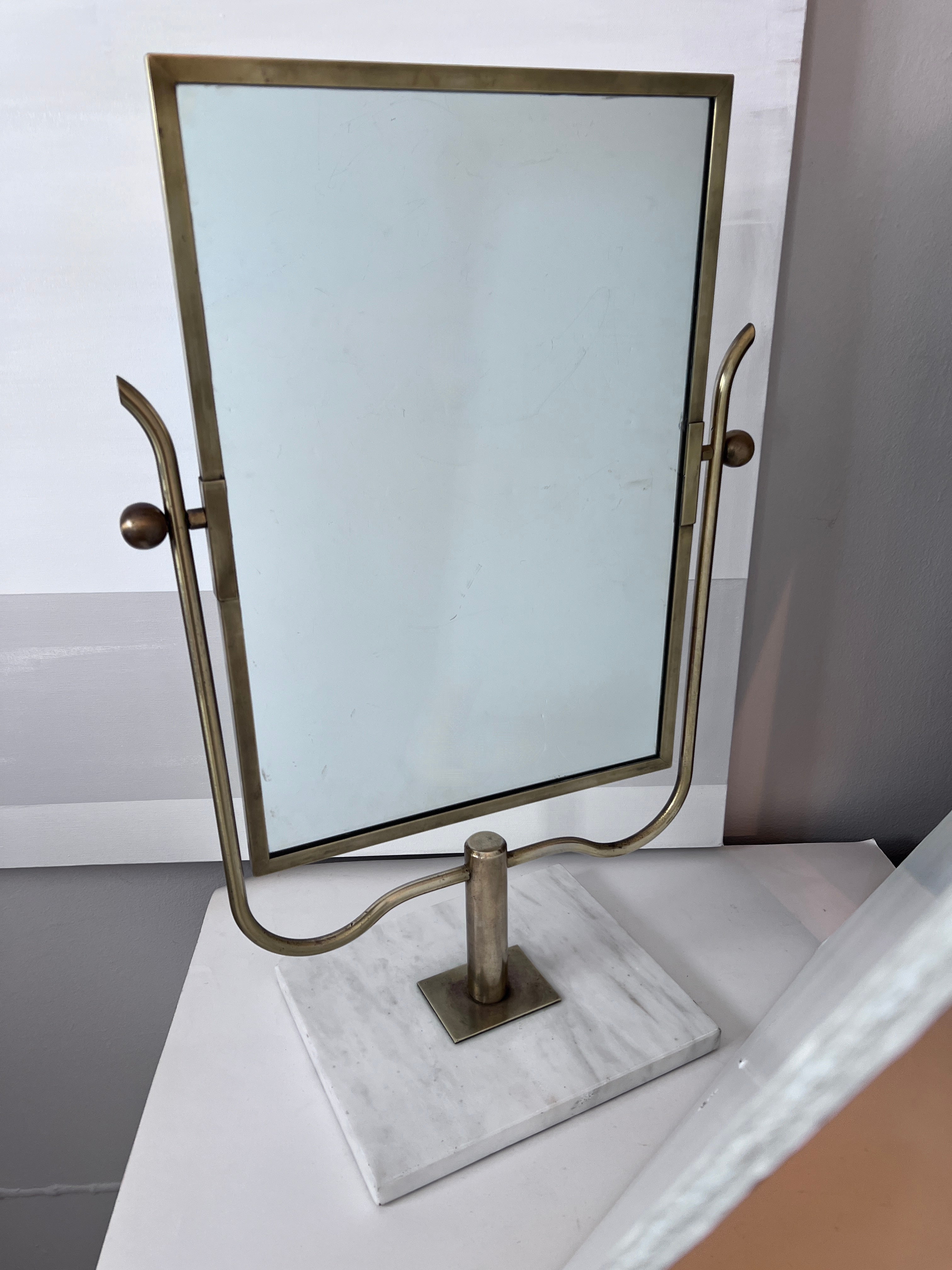 A stunning and graceful Vanity or Table Mirror with Brass frame and mounted on Carrara marble.  The piece, in the style of Mid Century Designer, Charles Hollis Jones.

The brass framework is very well done and has a lovely graceful shape with a