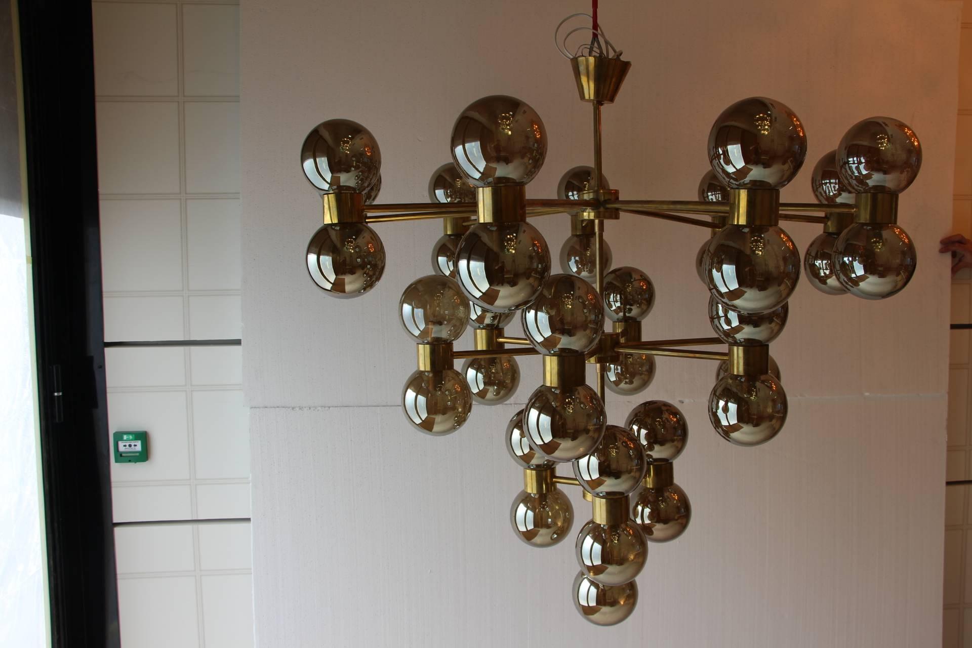 This very unusual three-tiered chandelier features thirty-seven lights and mercurised silver glass globes on a brass structure. When light is on, its globes turn to golden color and give a very warm golden color.
It has got a beautiful design, very