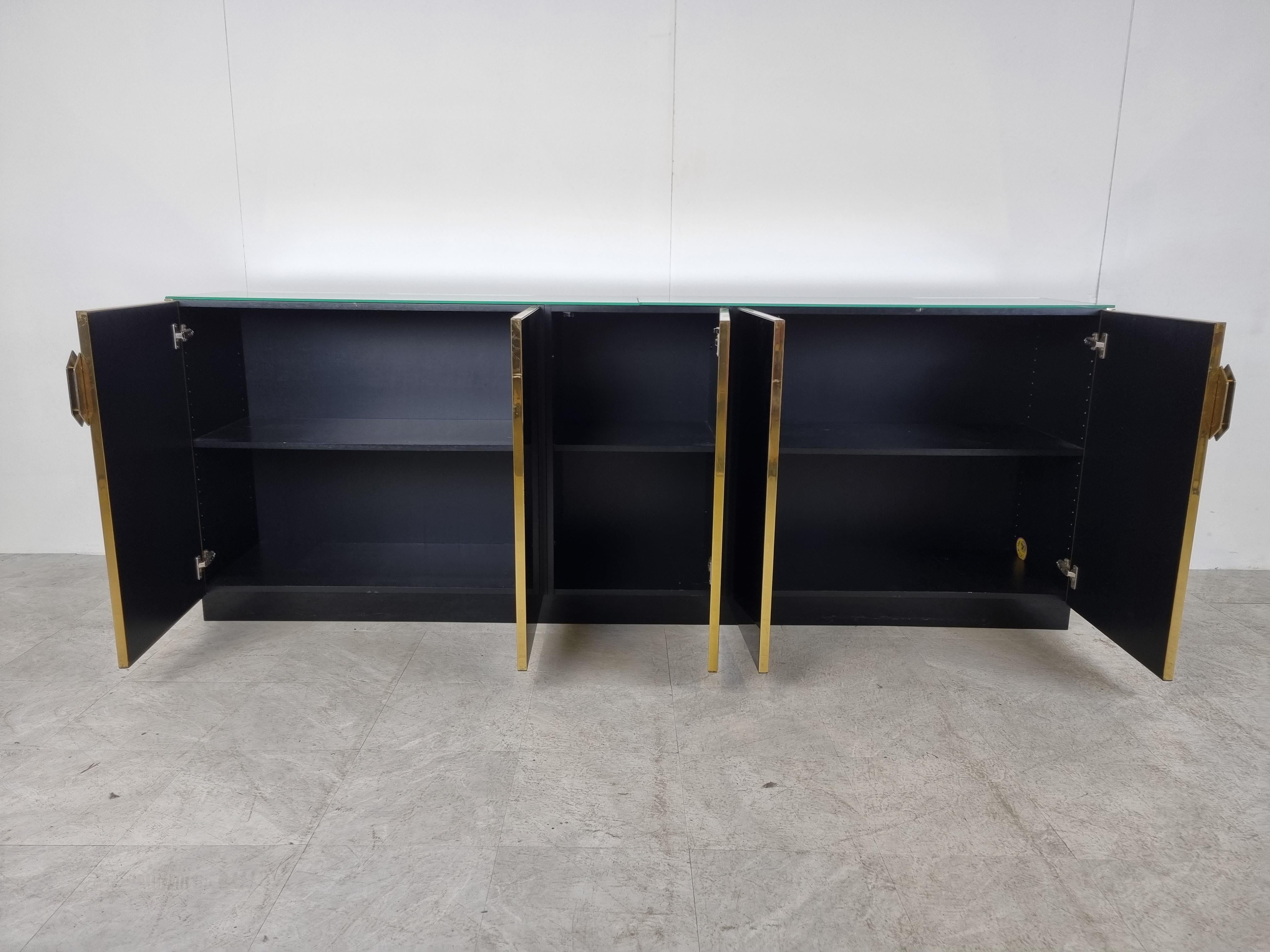 Luxurious seventies glamour sideboard by Maison jansen consitsing of black glass panels, brass handles and a mirrored glass top.

The handles are nicely designed and the mirrored top gives it a an extra touch.

Good condition.

1970s -