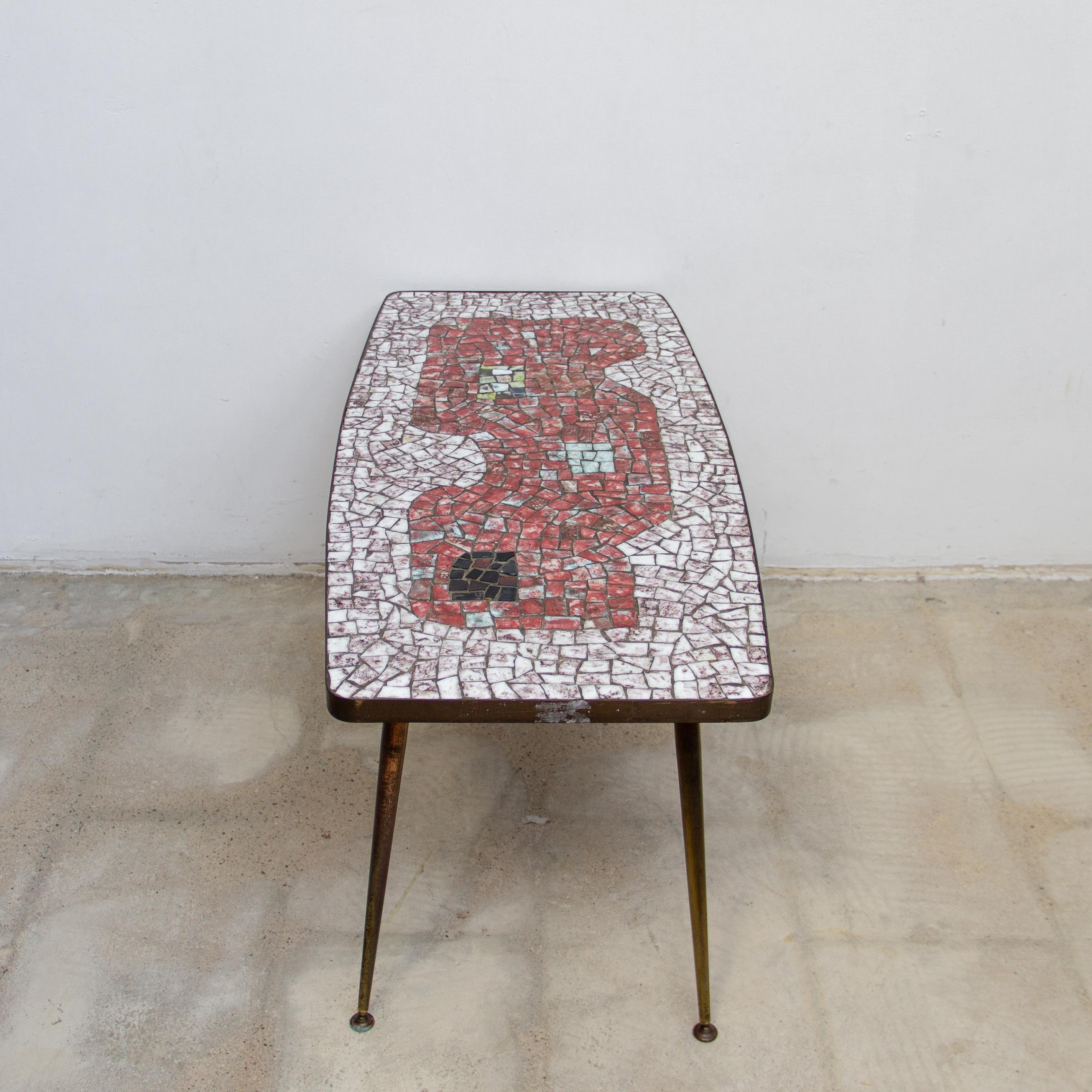 Mosaic top coffee table by the German sculptor Berthold Muller Oerlinghausen (1893-1979). The table has a rectangular shaped tabletop and a beautiful mosaic pattern of stone mosaic tiles and a brass rim and tapered brass legs. The colors of the