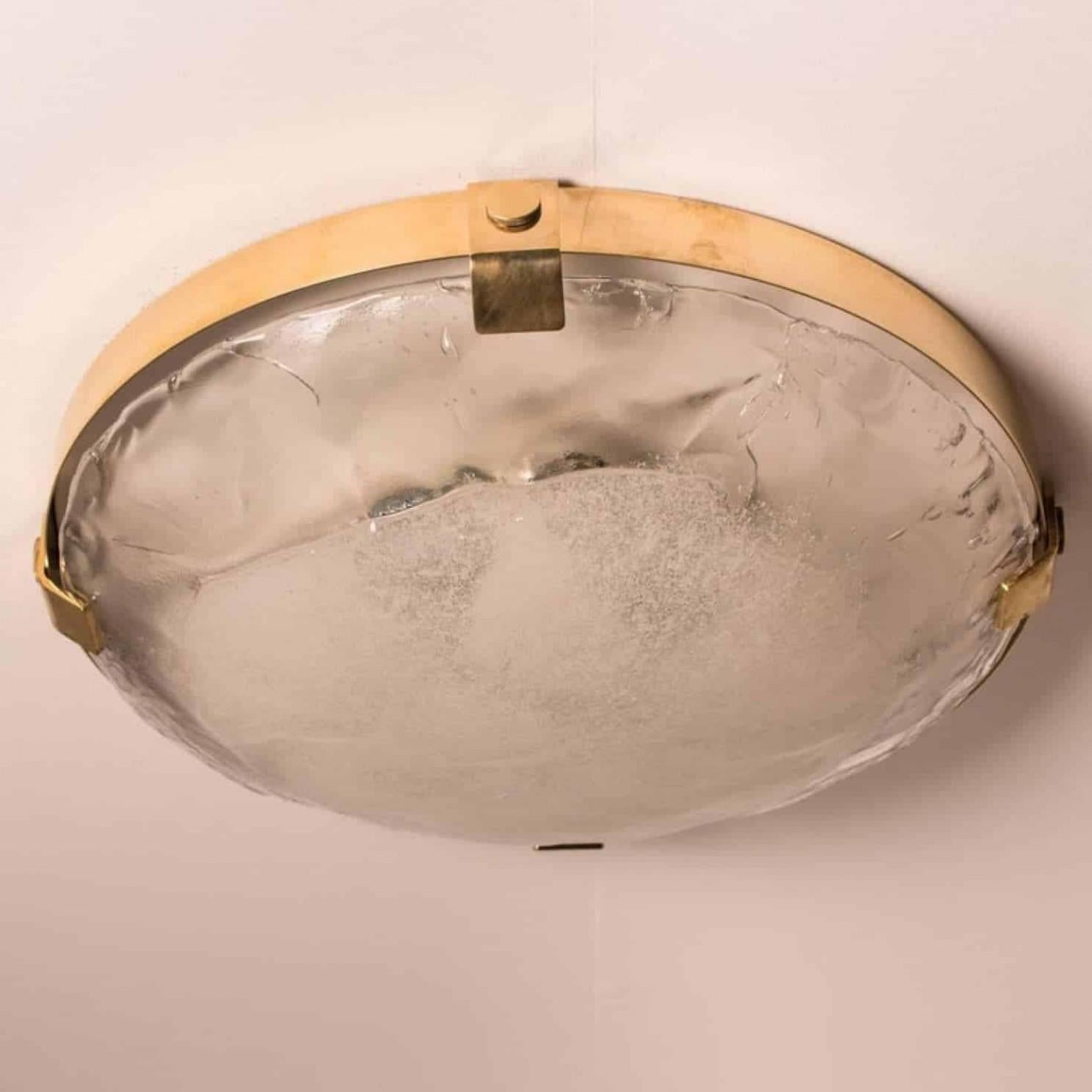 A high-end brass and murano glass flush mount by J.T. Kalmar, Vienna, Austria. Manufactured in the late 1960s-early 1970s.

The brass ring holds a huge heavy blown glass with four brass brackets. The glass has a beautiful textured structure.