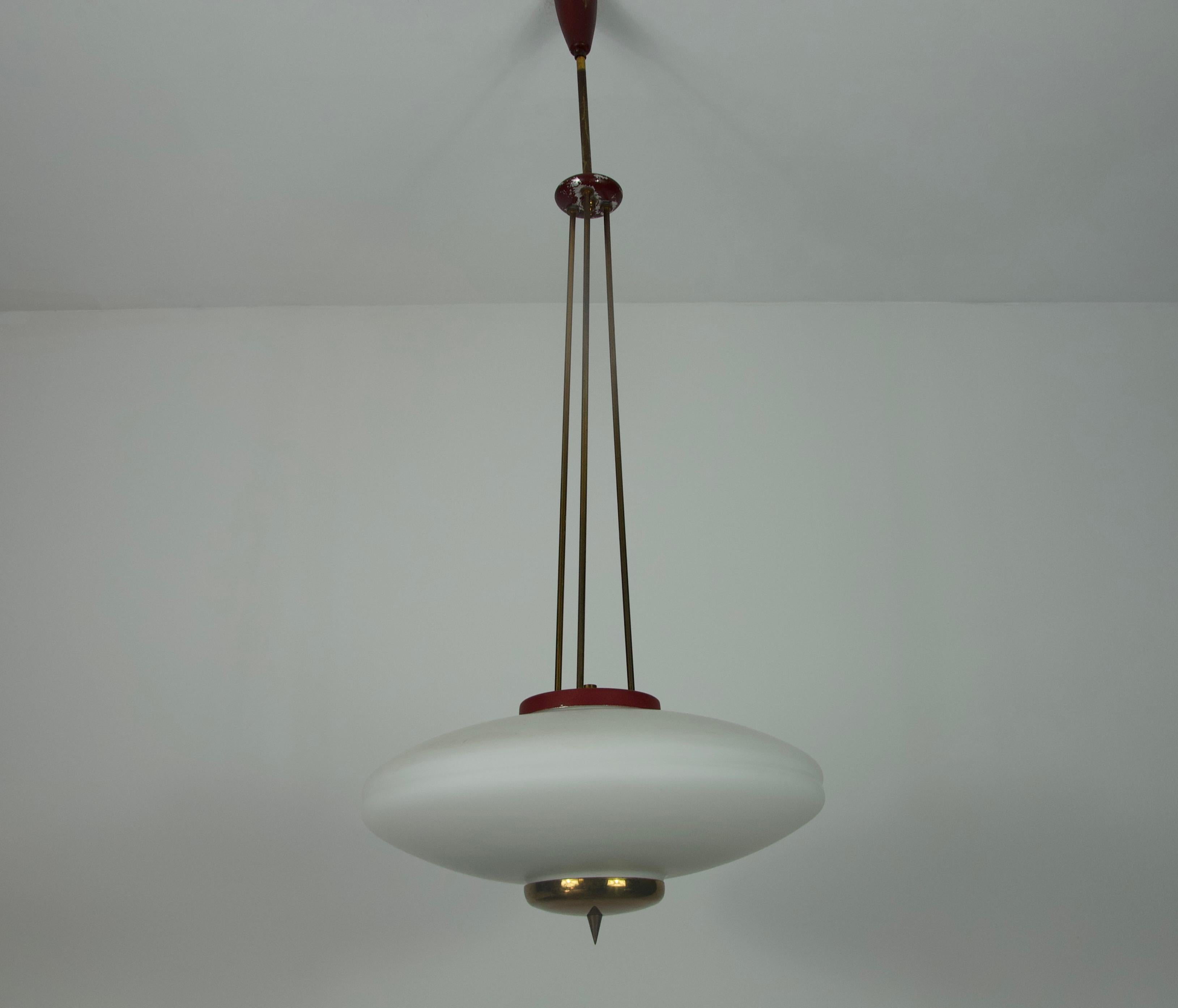 This elegant ceiling lamp, crafted by renowned Italian lighting manufacturer Stilnovo in the 1960s, is a striking example of mid-century modern design. It features a refined combination of opal glass and brass elements, suspended by three slender
