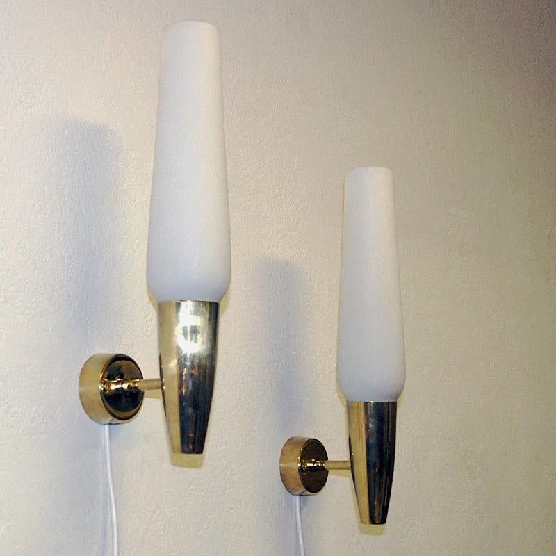 Hübsches Paar Wandlampen aus Opalglas von Asea Sweden aus den 1950er Jahren, mattiert. Klassische Wandleuchten mit zylinderförmigen Glasschirmen, die von einer konischen Messinghalterung gehalten werden, die an einem runden Wandsockel aus Messing