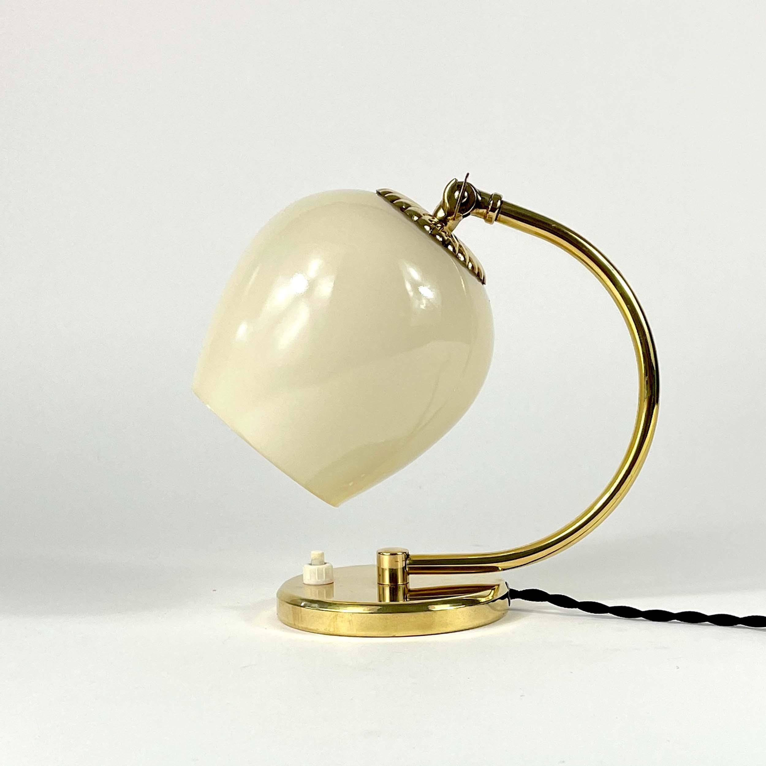This beautiful table or bedside lamp was designed and manufactured in Finland in the late 1940s to 1950s. It features a cream colored opaline lampshade and brass hardware.

The light has been rewired with new black fabric cord and requests one